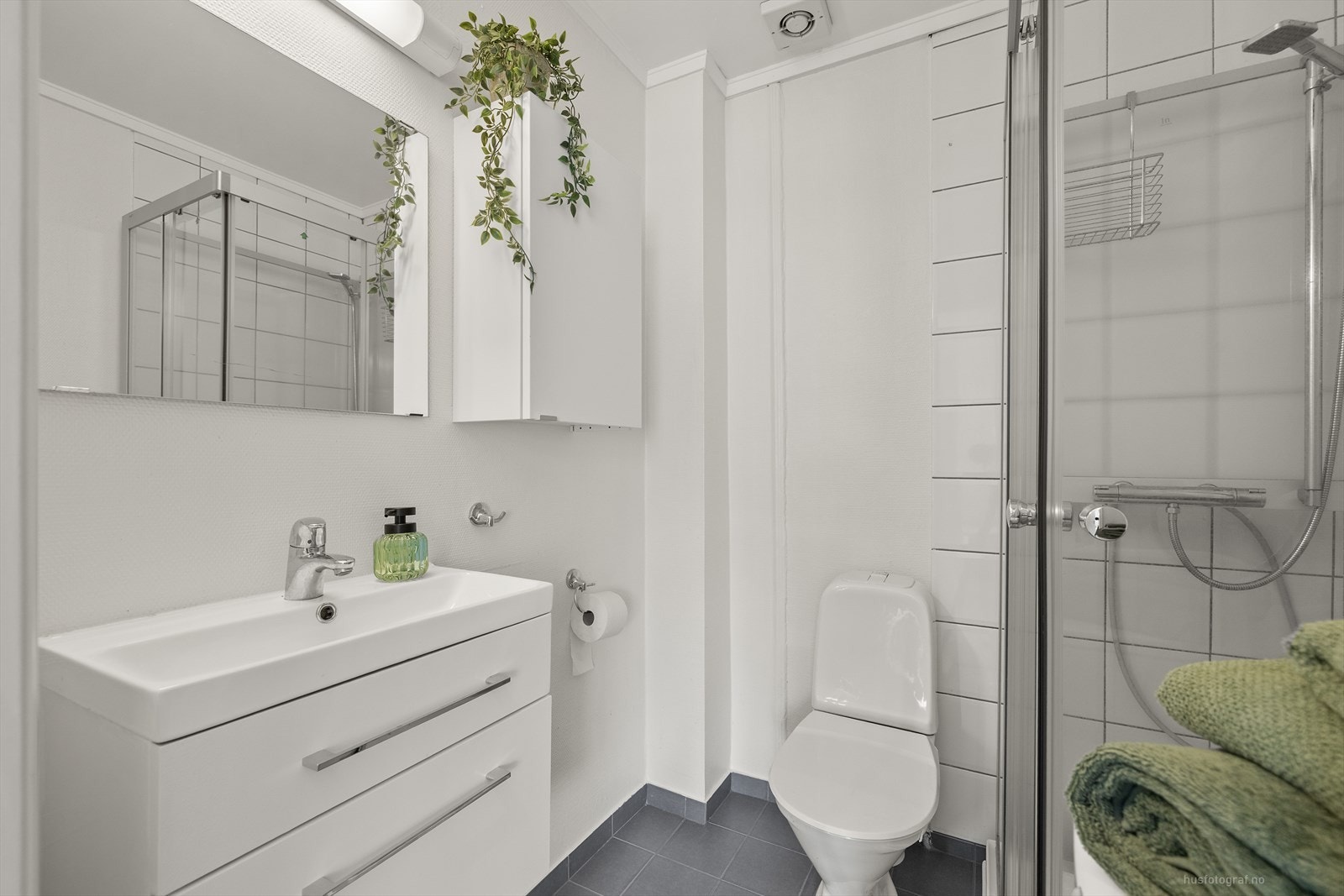 Det er flislagt gulv, strie på vegger og servant med baderomsinnredning Galleribilde