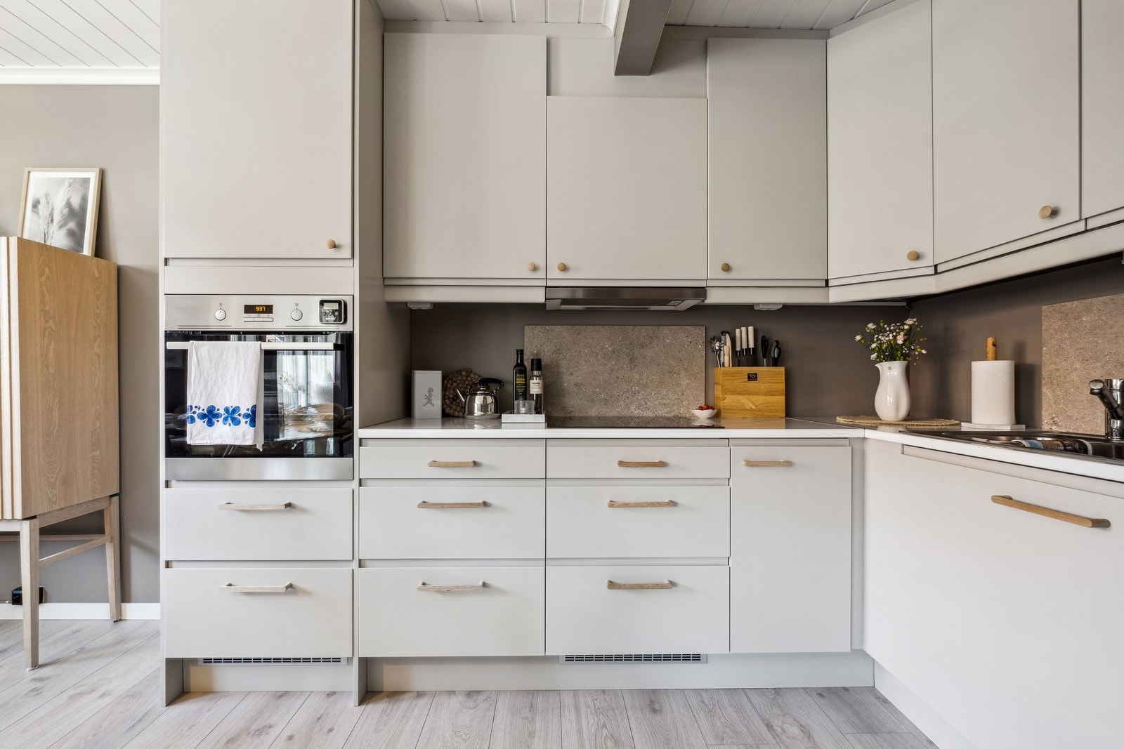 Kjøkkenet. Kjøkkenet er fra Epoq med integrert
platetopp, stekeovn og oppvaskmaskin og det ble malt våren 2024 og påmontert hvitpigmenterte håndtak/knopper i eik og flis som skvett plater. Her er det også montert opp ny led list som gir godt med lys. Galleribilde