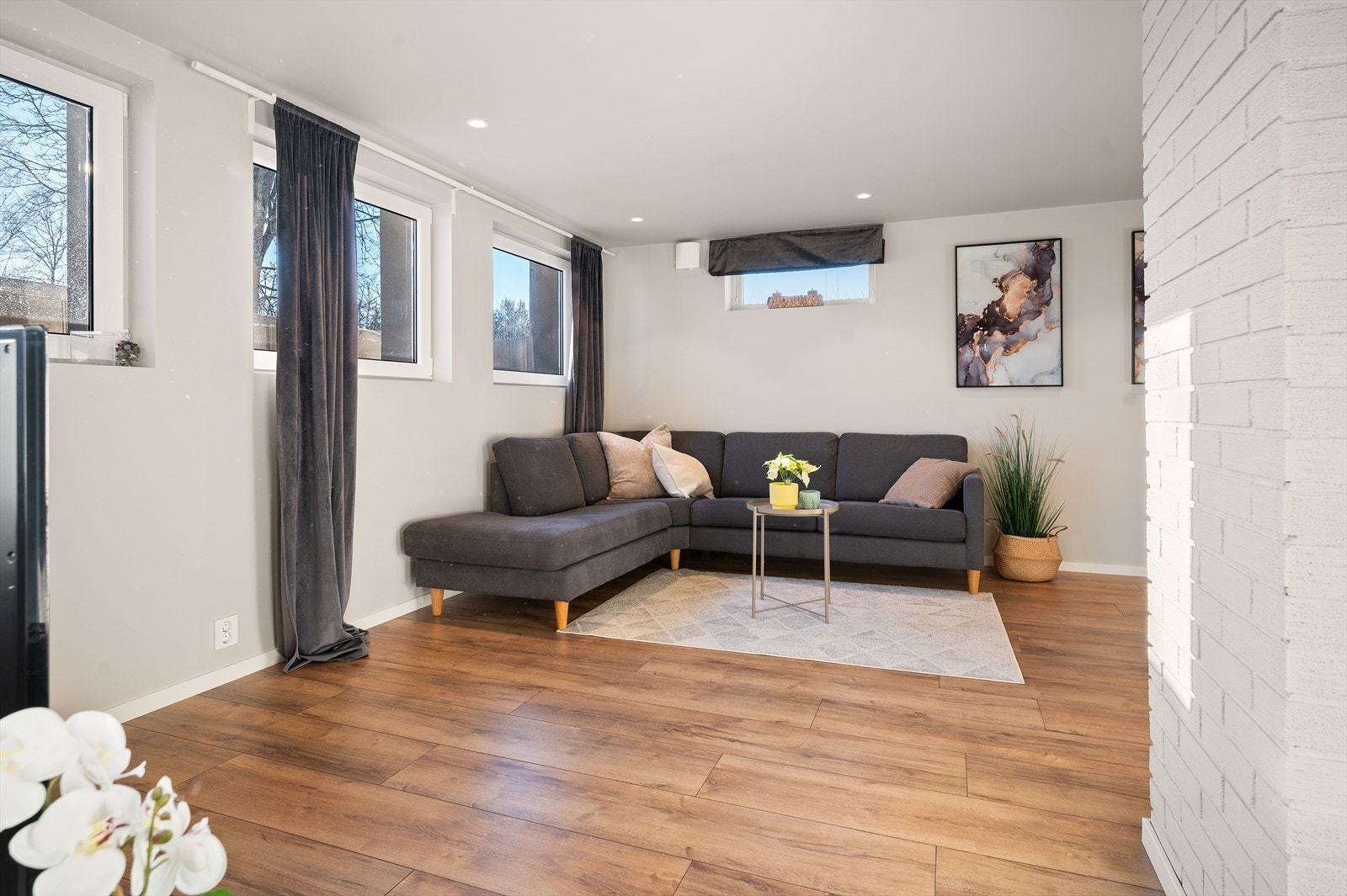 Lys og romslig stue i kjelleretasjen med åpen løsning mot kjøkkenet. God plass til både sofagruppe og spisebord, noe som skaper en innbydende atmosfære. Galleribilde