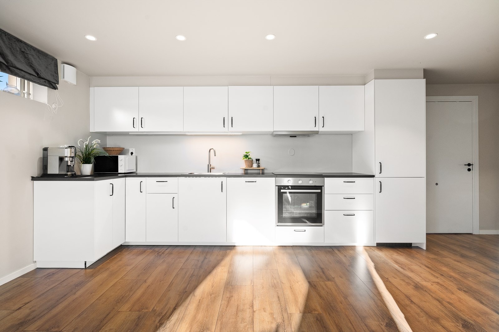 Stilrent og funksjonelt kjøkken med hvite fronter og god skap- og benkeplass. Galleribilde