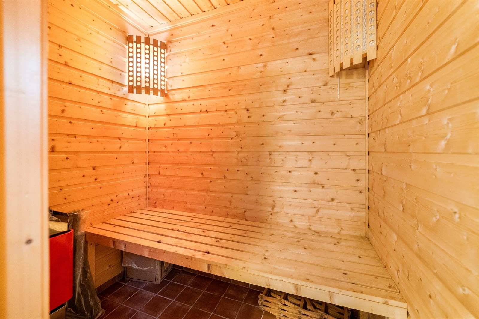Det er etablert sauna/badstue i underetasjen, med overflater av panel og fliser på gulv. Det er montert elektrisk ovn i rommet. Galleribilde
