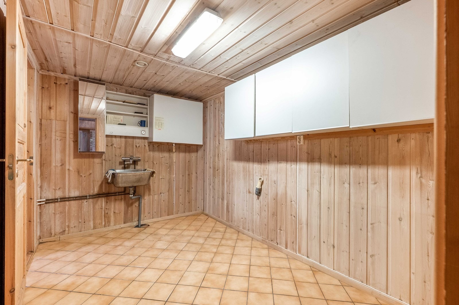 Praktisk vaskerom med opplegg for vaskemaskin og tørketrommel, samt utslagsvask i rustfritt stål. Galleribilde