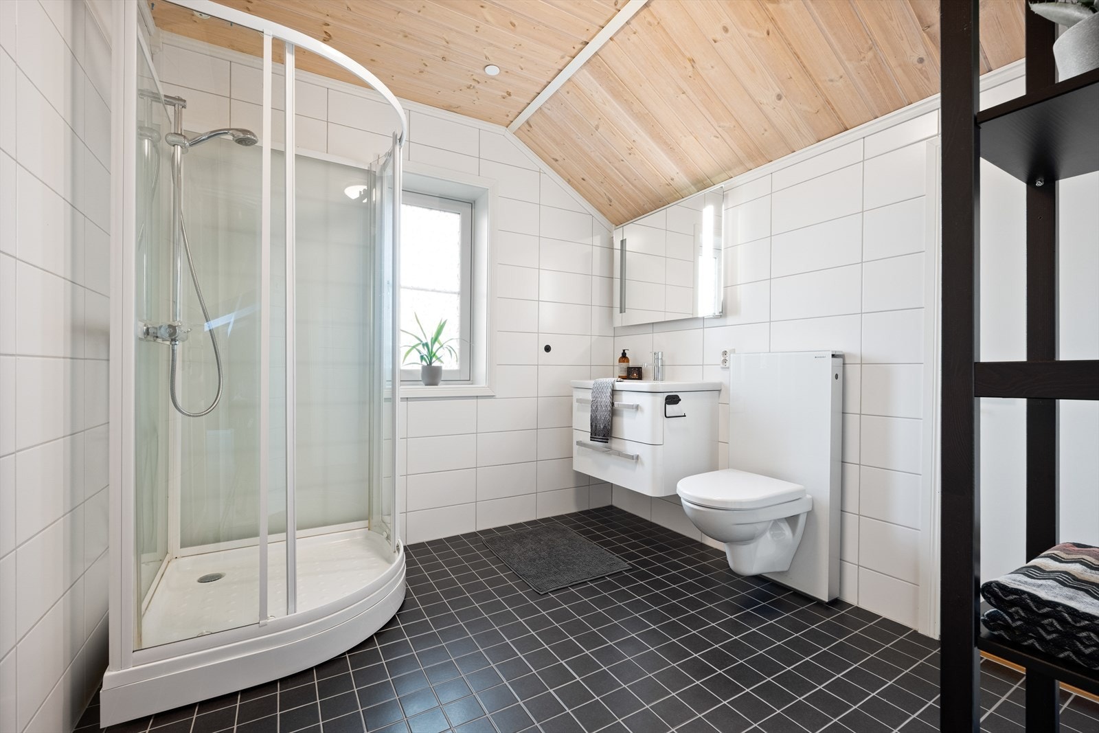 Bad i loftsetasjen med servant i innredningen, vegghengt toalett og dusjkabinett. Galleribilde
