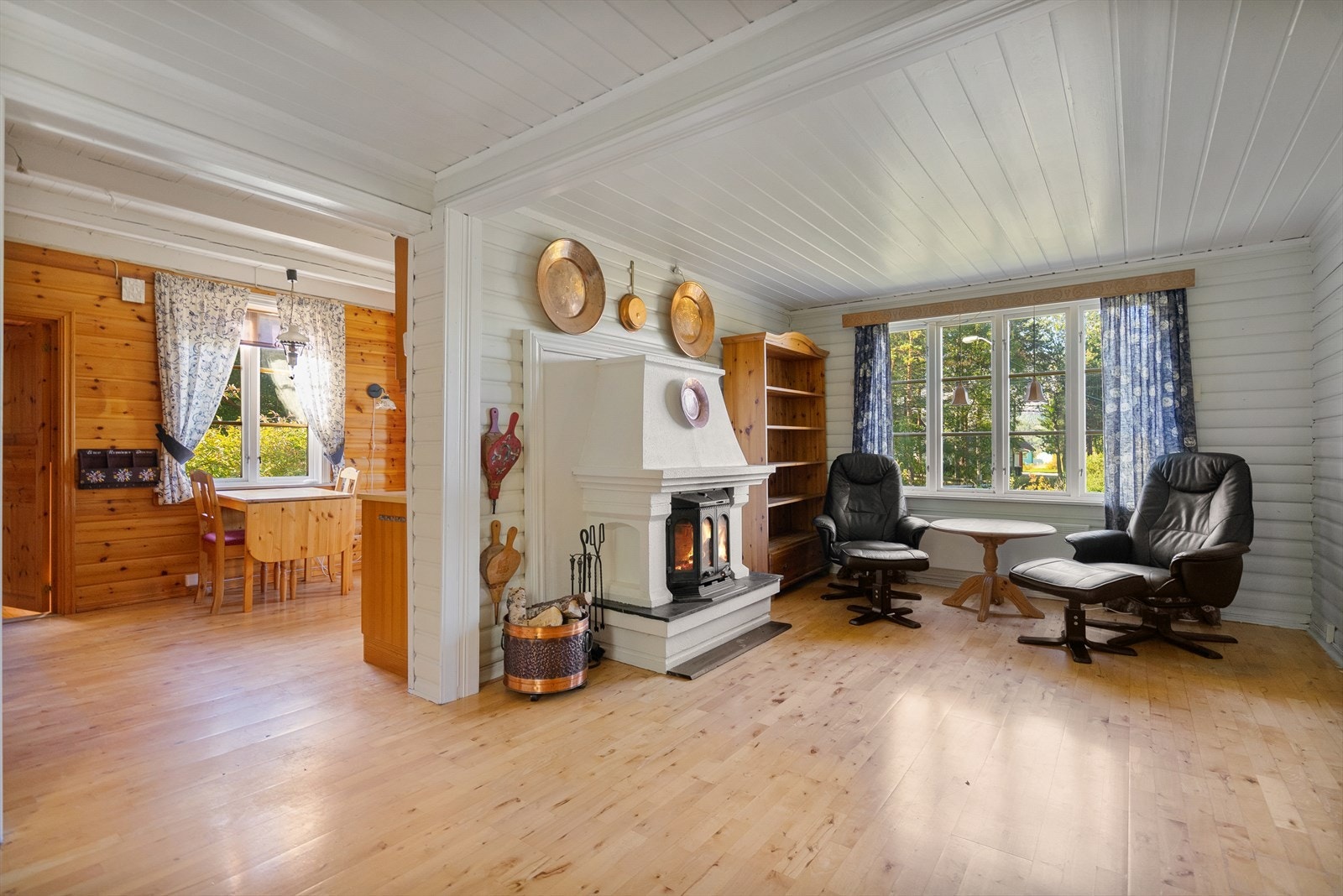 Romslig stue med hvitmalt panel og peisovn som gir en lun atmosfære på kalde dager Galleribilde