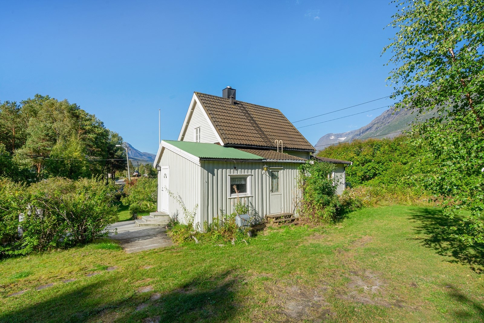 Husets bakside med hageareal og lune uteplasser - uteområdet gir fine muligheter for sommerliv og utendørs sammenkomster Galleribilde