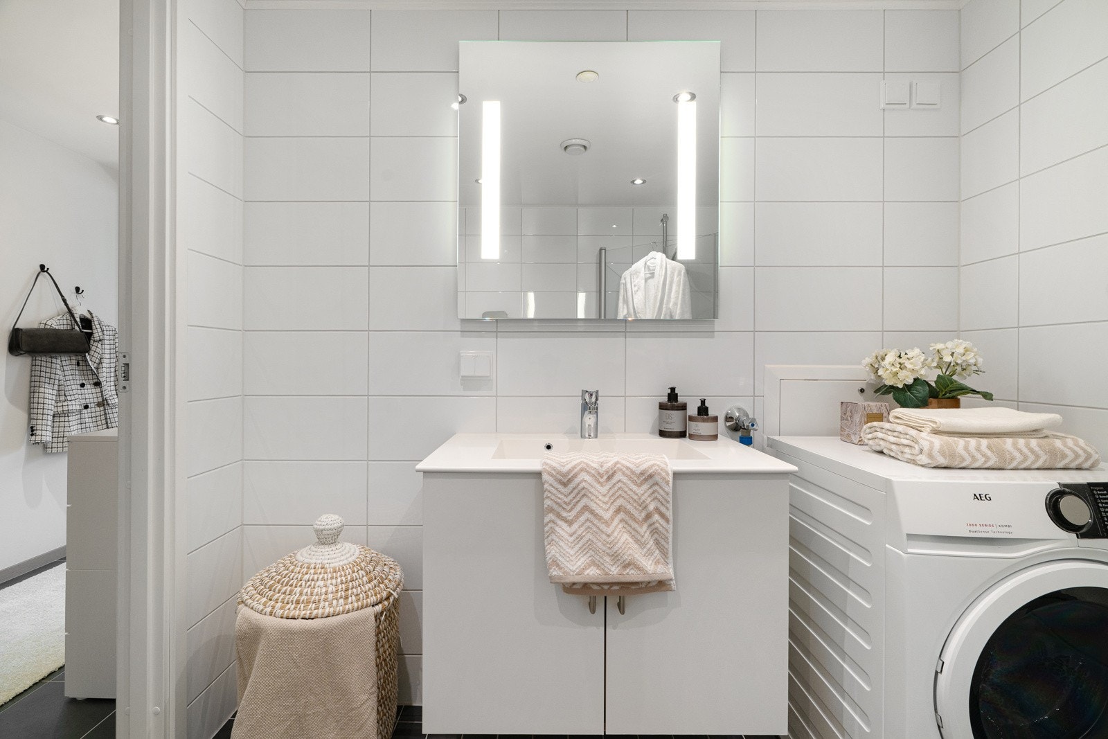 Badet er utstyrt med heldekkende servant over skap, vegghengt toalett og opplegg for vaskemaskin. Dusjnisjen har innfellbare dører i glass som gjør at plassen kan utnyttes til det fulle. Varmekablene i gulvet gir en behagelig temperatur. Galleribilde