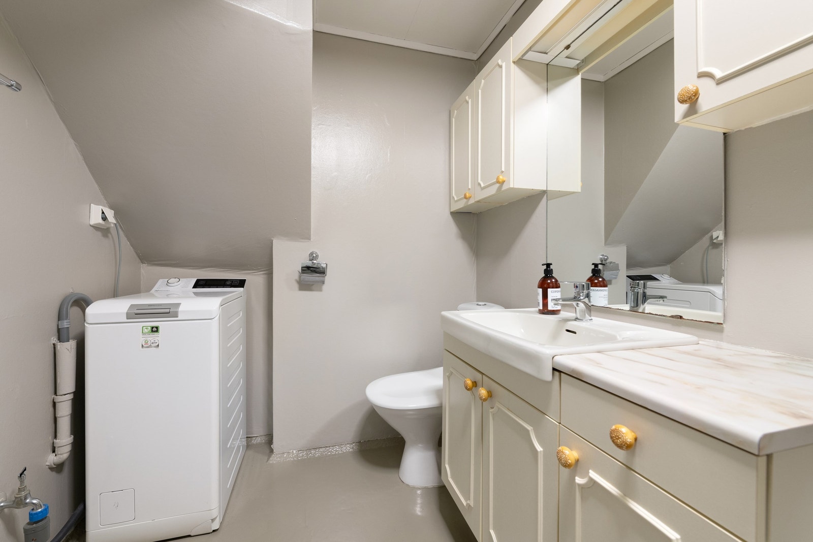 Bad med malt betonggulv med gulvvarme. Baderomsinnredning med servant og armatur. Gulvstående toalett Galleribilde