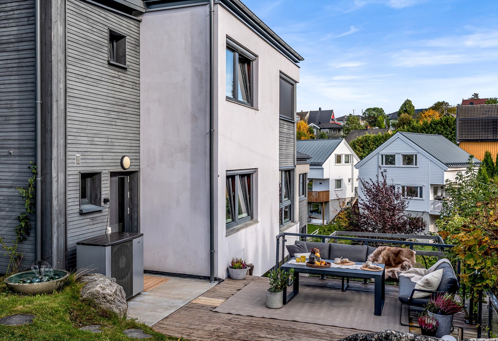 Boligen reiser seg elegant i terrenget, med en kombinasjon av puss og trekledning. Galleribilde
