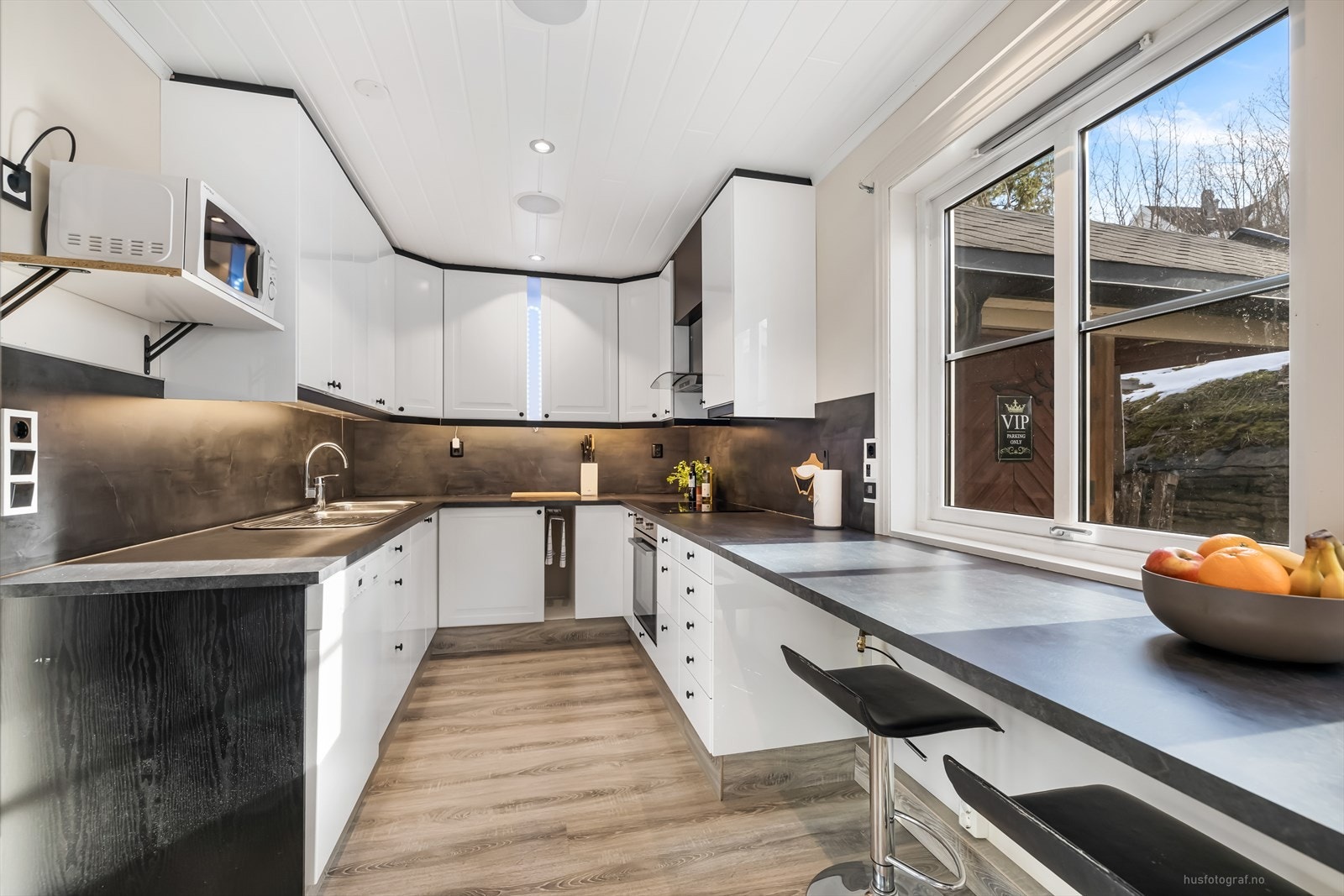 Stilrent og moderne kjøkken med integrerte hvitevarer, god arbeidsflate og store vinduer som gir rikelig med dagslys. Galleribilde