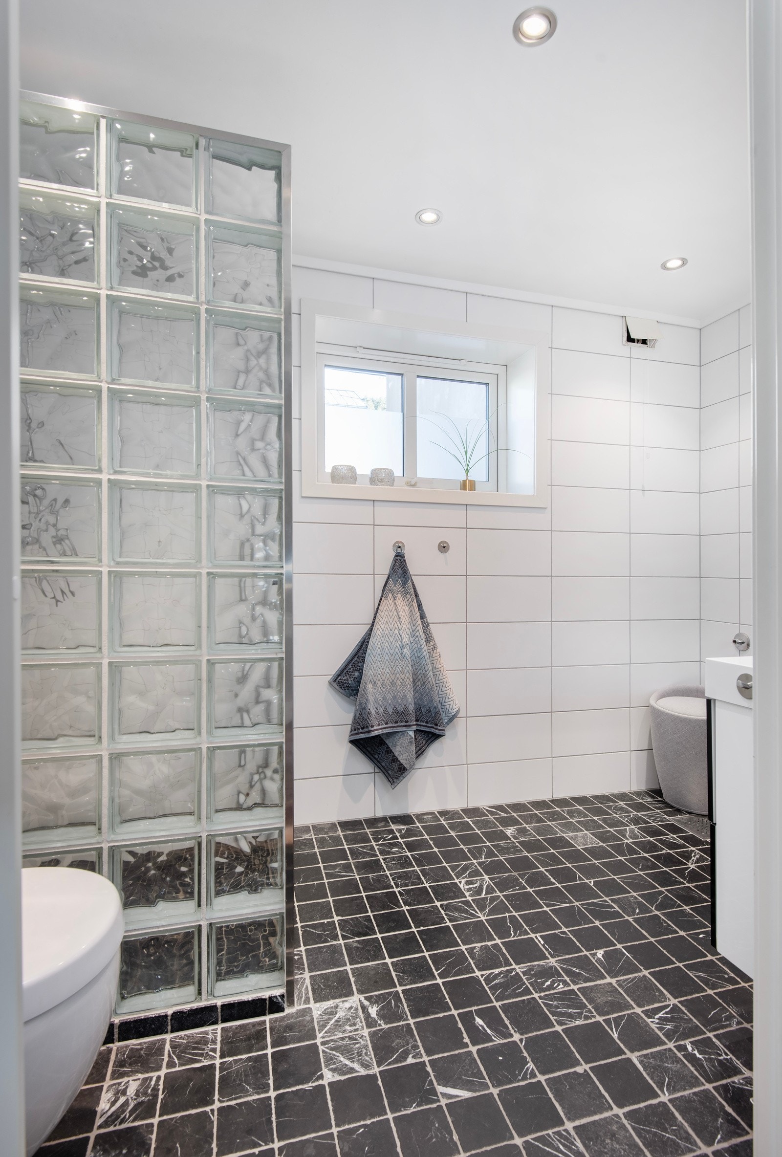 Helfliset bad fra 2009 med elektriske varmekabler. Innredet med vegghengt toalett, dusjhjørne med vegg i glassbyggerstein og glassdører. Galleribilde