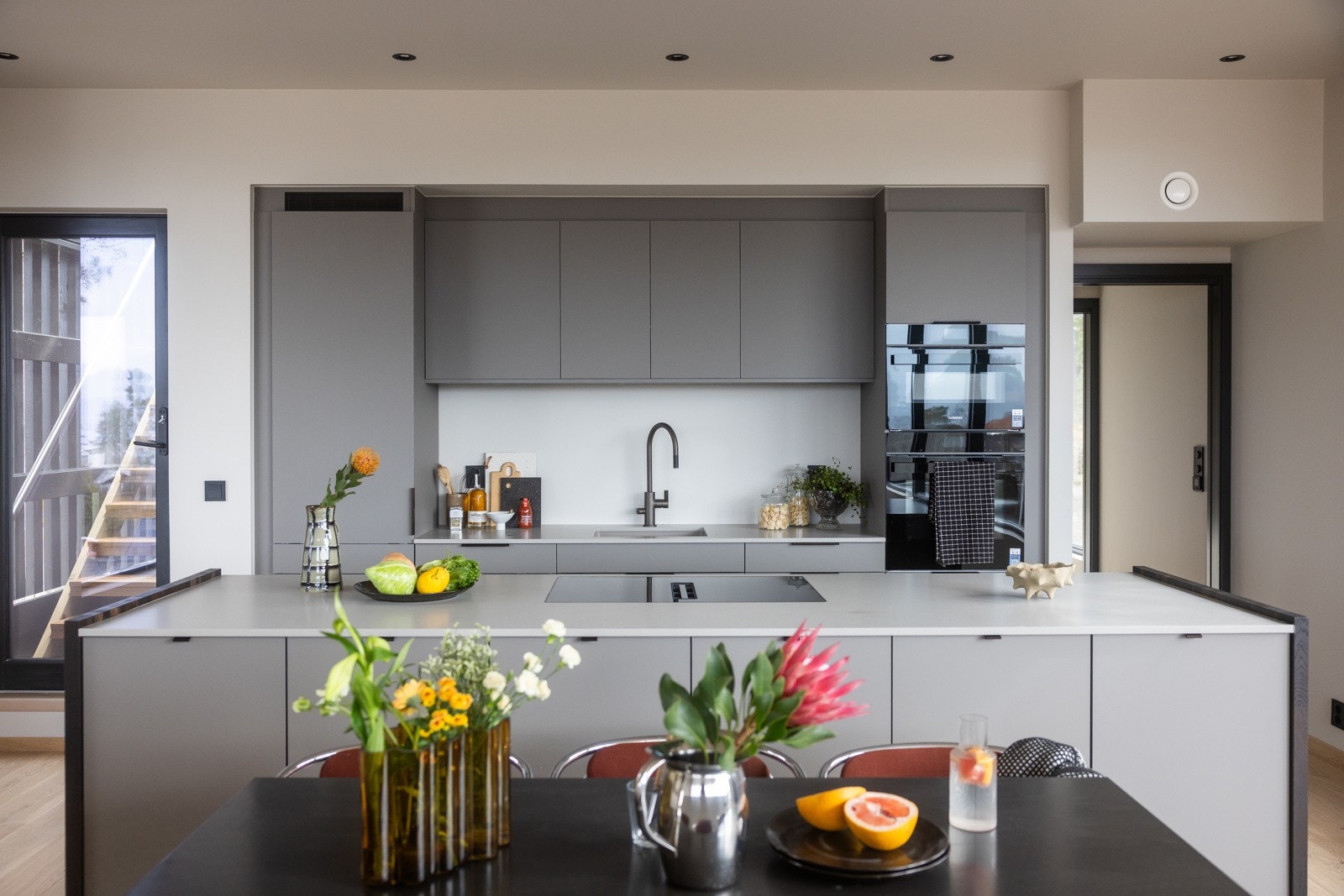 Innredningen har et stilrent og tidsriktig uttrykk med grå fronter og benkeplate i sten, og byr på rikelig med både oppbevaringsplass og benkeflate for matlaging. Galleribilde