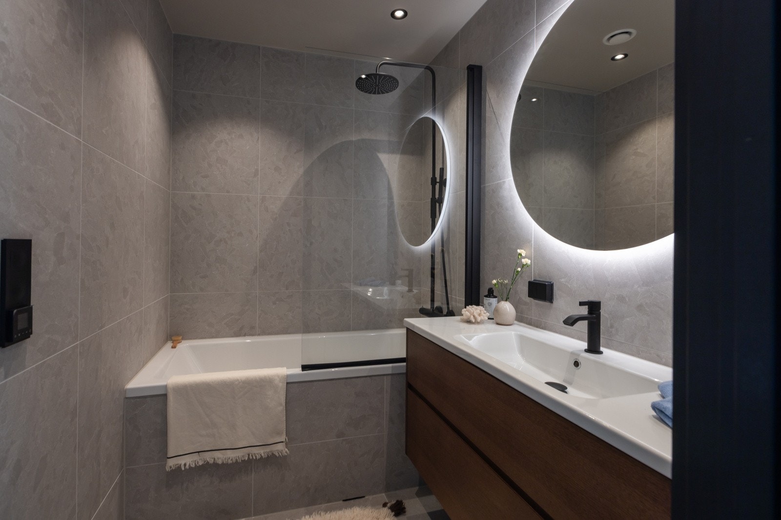 Badet som tilhører de tre soverommene i hovedetasjen er stilfullt innredet med beige-tonede fliser, vegghengt toalett, innmurt badekar med dusj samt en servant med skuffer under. Galleribilde