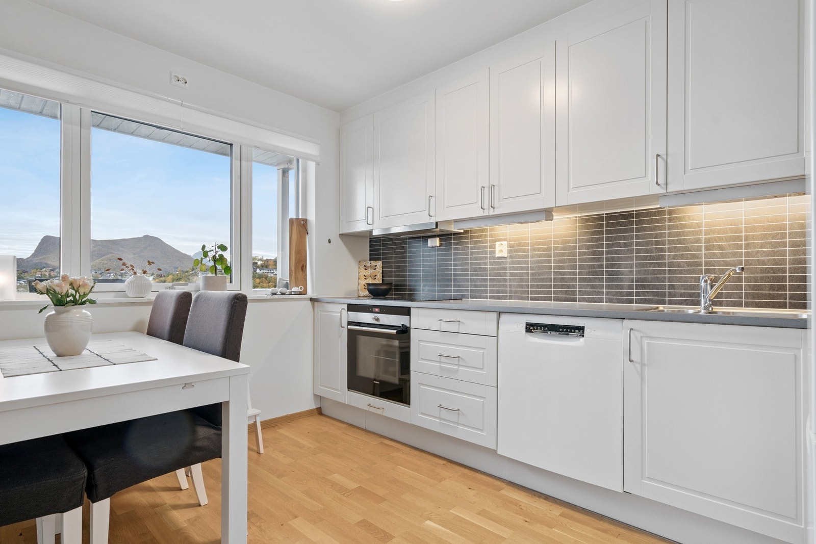 Pen lys kjøkkeninnredning med integrert komfyr og platetopp Galleribilde