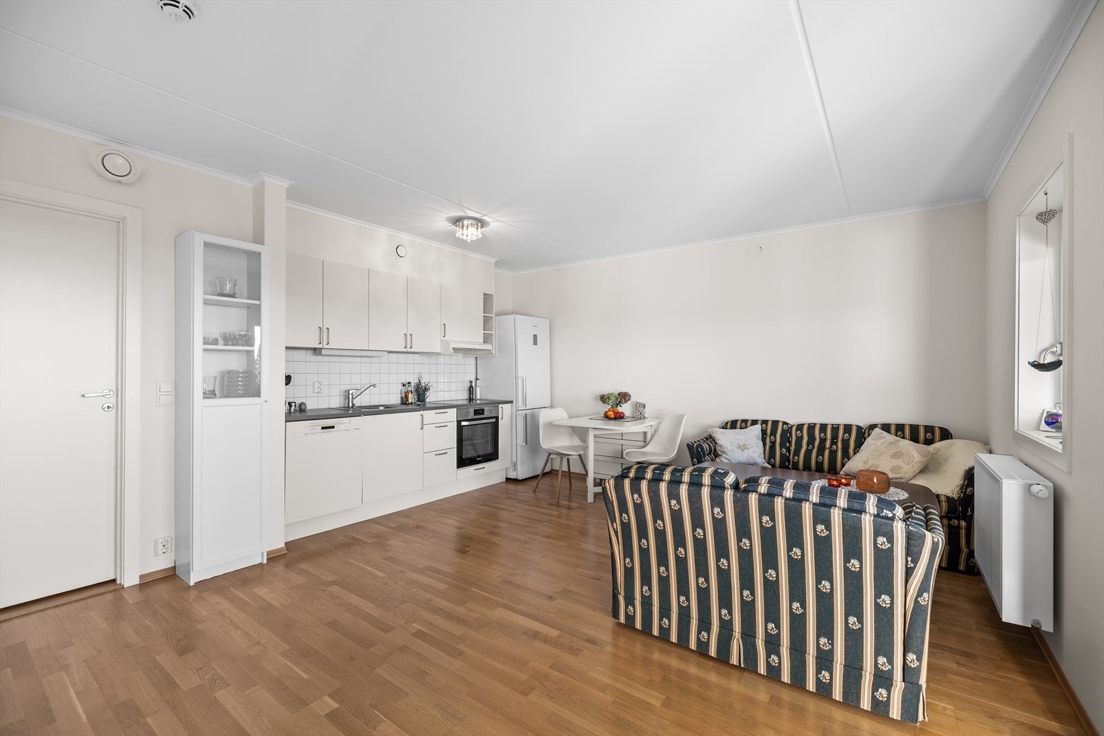 De lyse, malte veggene og den elegante trestavs eikeparketten på gulvet gir et tidløst og stilrent uttrykk, som enkelt lar seg kombinere med ulike interiørstiler. Rommet oppleves både moderne og varmt - et sted man umiddelbart føler seg hjemme. Galleribilde