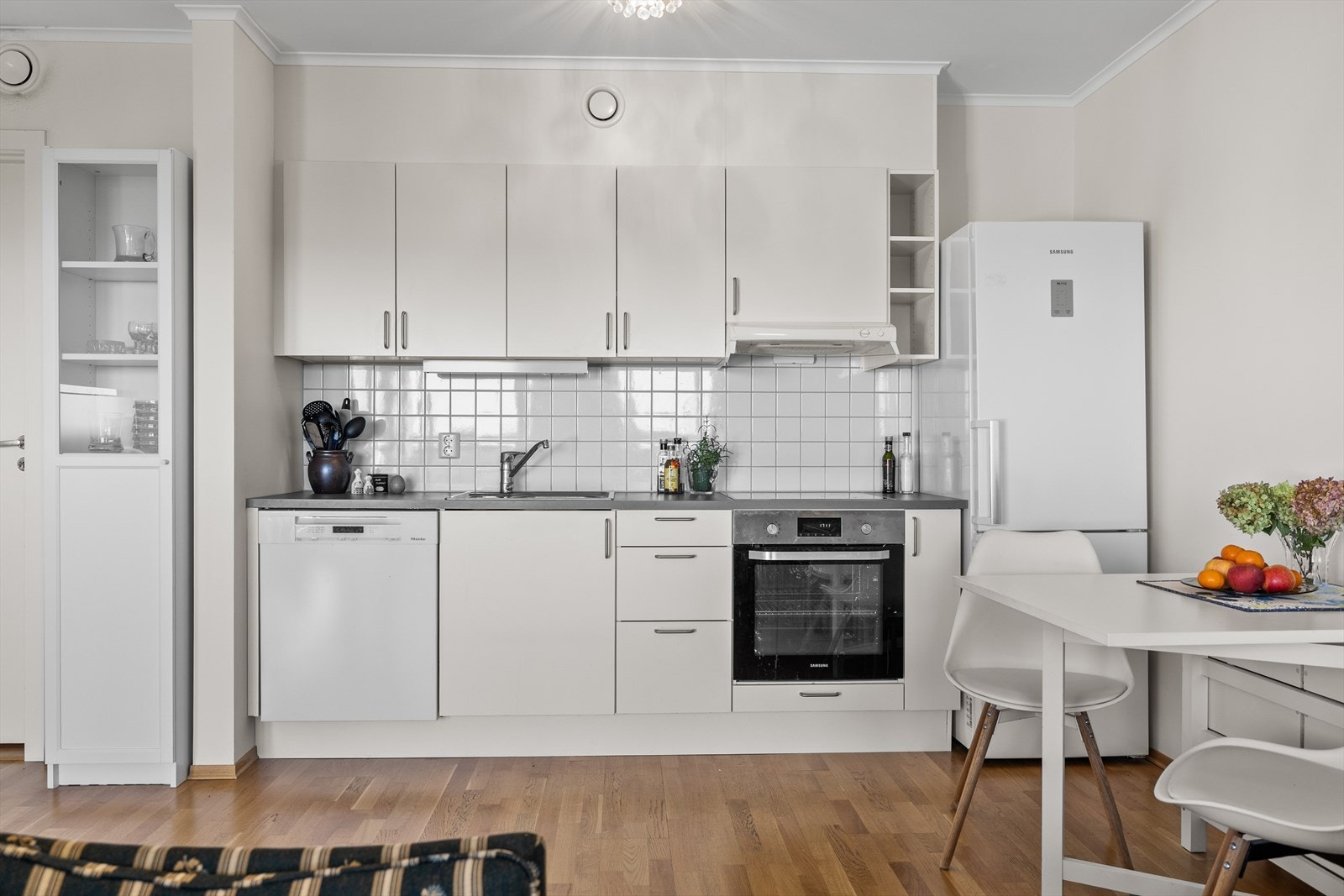 Kjøkkenet er godt utstyrt med integrerte hvitevarer som platetopp og stekeovn, samt både komfyrvakt og automatisk vannstoppesystem for ekstra trygghet i hverdagen. Løsningen er smart planlagt for å utnytte plassen maksimalt. Galleribilde