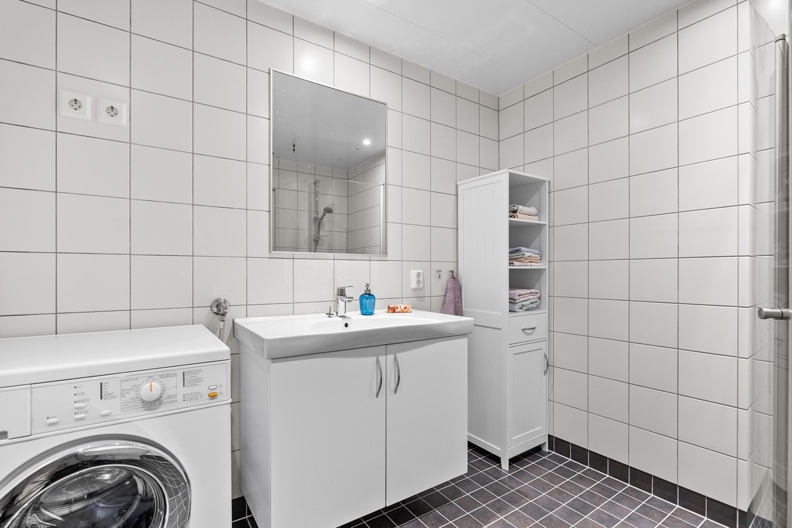 Innredningen består av nedfelt servant i stilren baderomsinnredning, veggmontert toalett og dusjhjørne med glassvegger - en løsning som gir både romfølelse og god funksjonalitet. Galleribilde