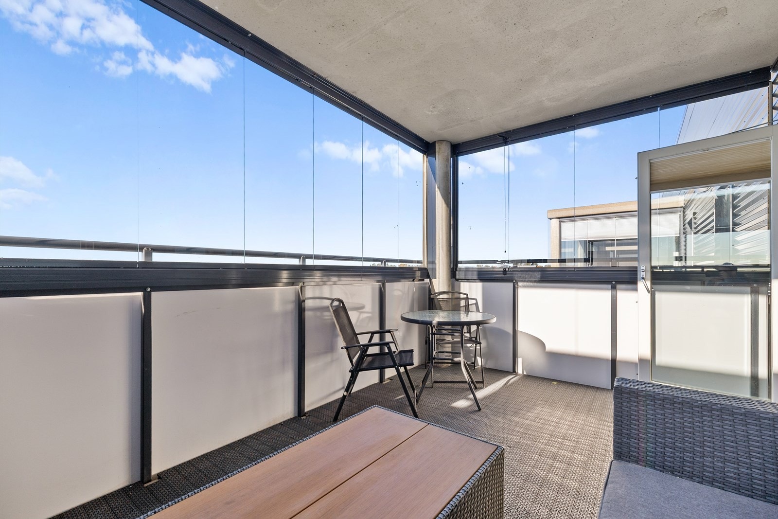 Den innglassede balkongen er romslig og gir deg et fantastisk uterom du kan bruke store deler av året. Her er det god plass til en innbydende loungeavdeling med myke puter og grønne planter, samt et lite spisebord. Galleribilde