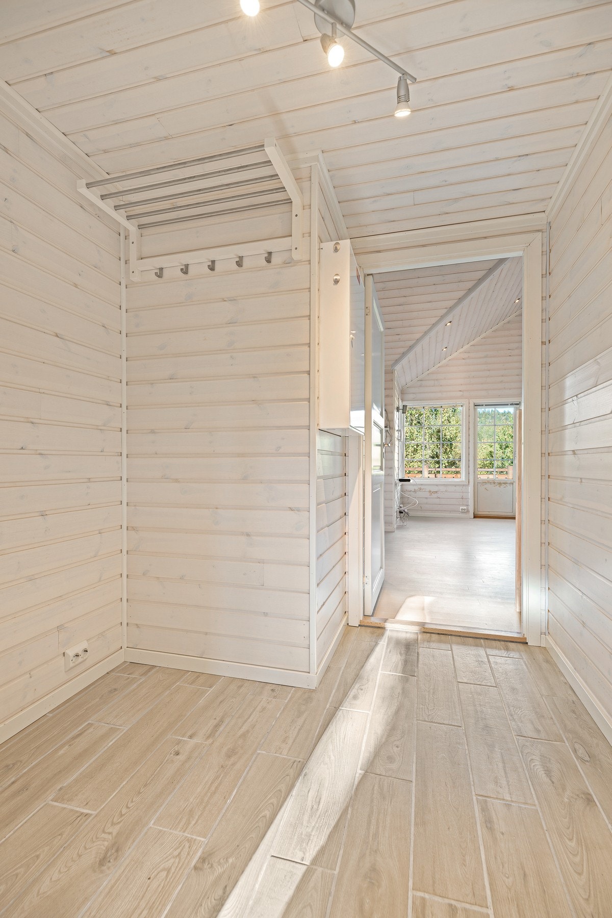 Hytta har en pen entré med lysmalt panel på veggene og matchende fliser på gulvet. Galleribilde