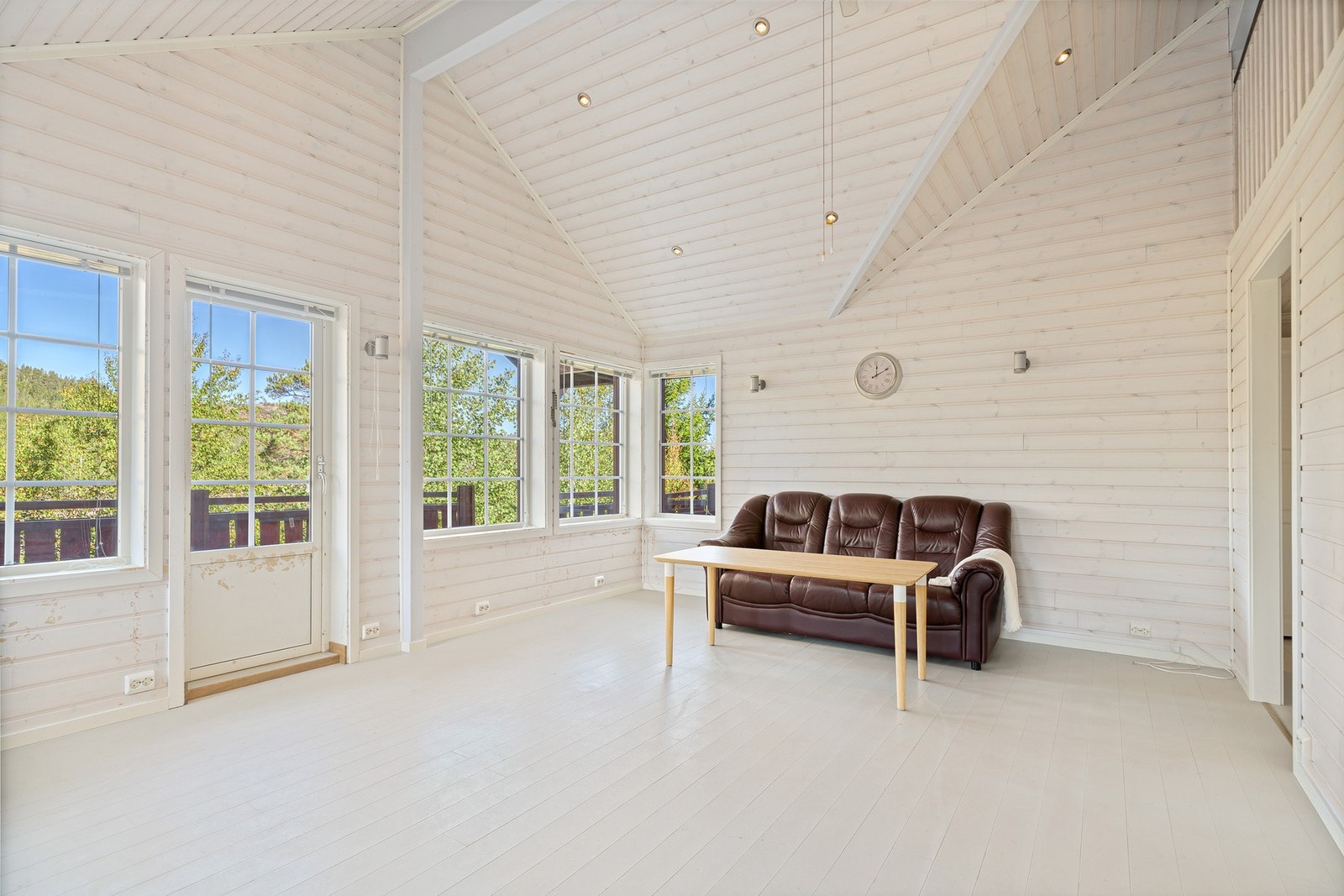 Dagslyset strømmer inn via store sprossevinduer i allrommet. Galleribilde