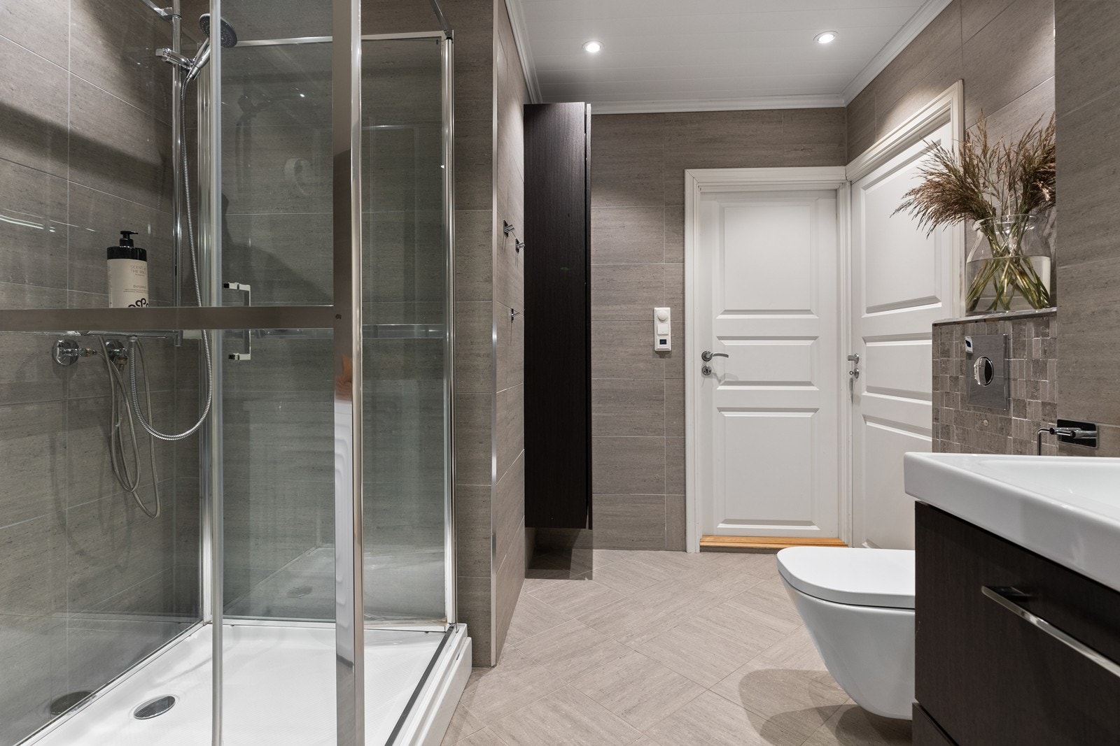 Moderne bad med dusjkabinett, vegghengt wc og servant med skuffeseksjon. Galleribilde