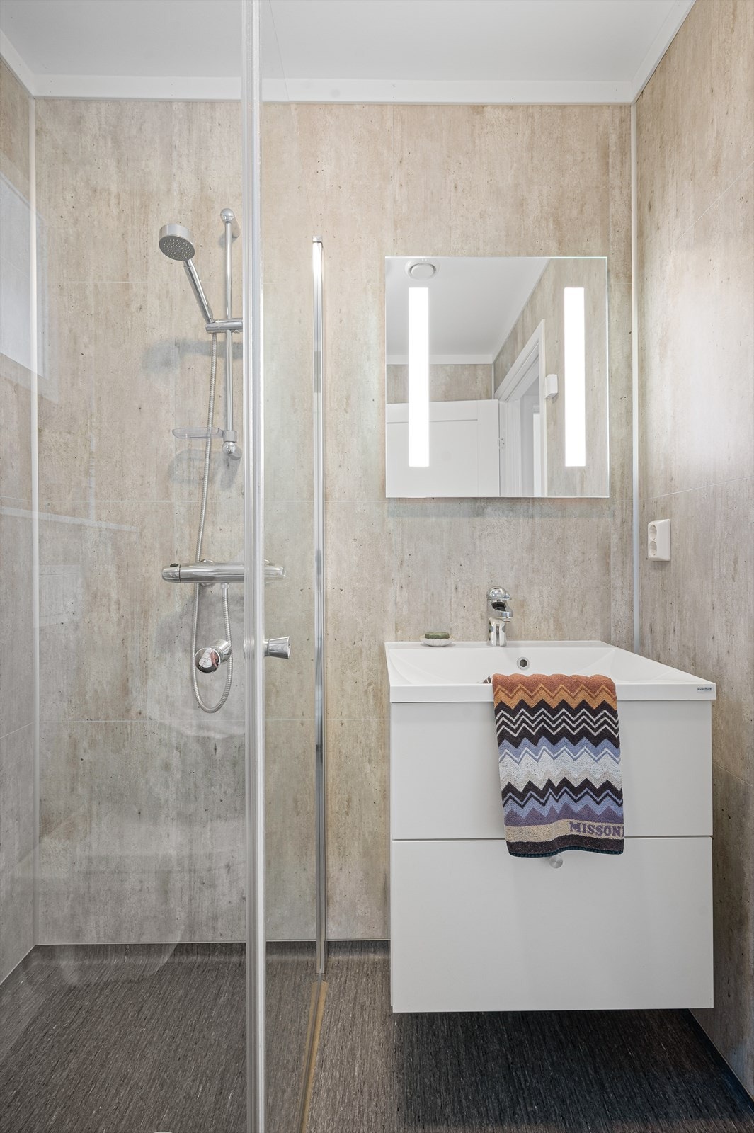 Belegg på gulv og våtromsplater på vegger. Malt overflate i himling. Gulvvarme. Utstyrt med innfellbare dusjdører, servantskap, veggmontert wc og mekanisk avtrekk. Galleribilde