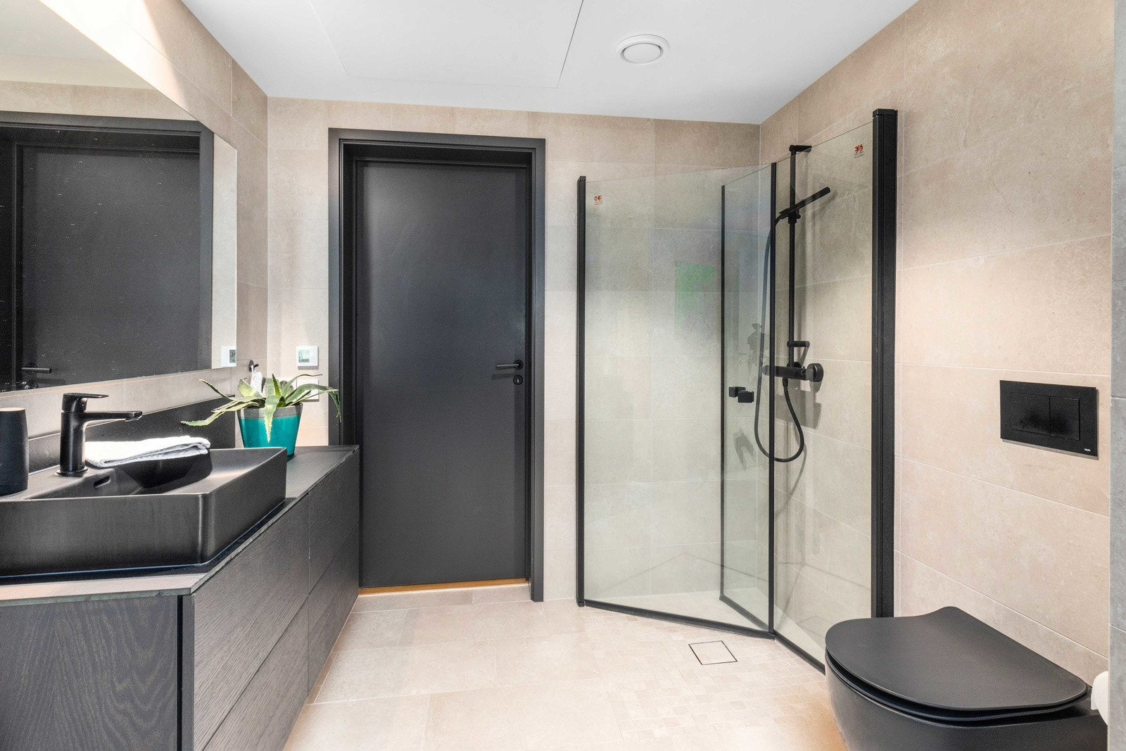 Badet er stort med både dusjhjørne, vegghengt toalett, baderomsinnredning og opplegg til vaskemaskin Galleribilde