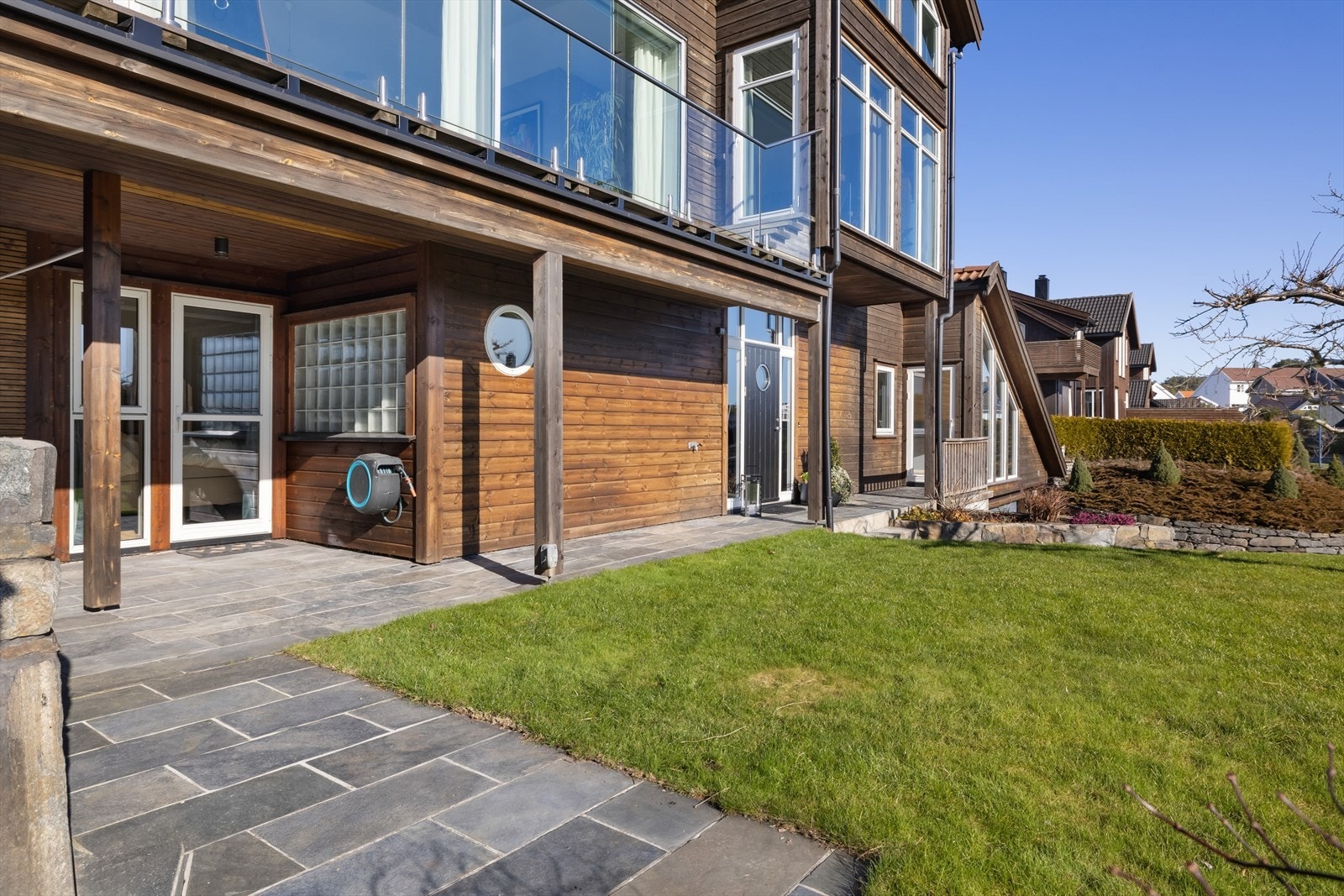 Eiendommen ligger i ett skrående terreng og utvendig utformet i flere nivåer med plen, terrasser og stenlagte uteplasser. Galleribilde