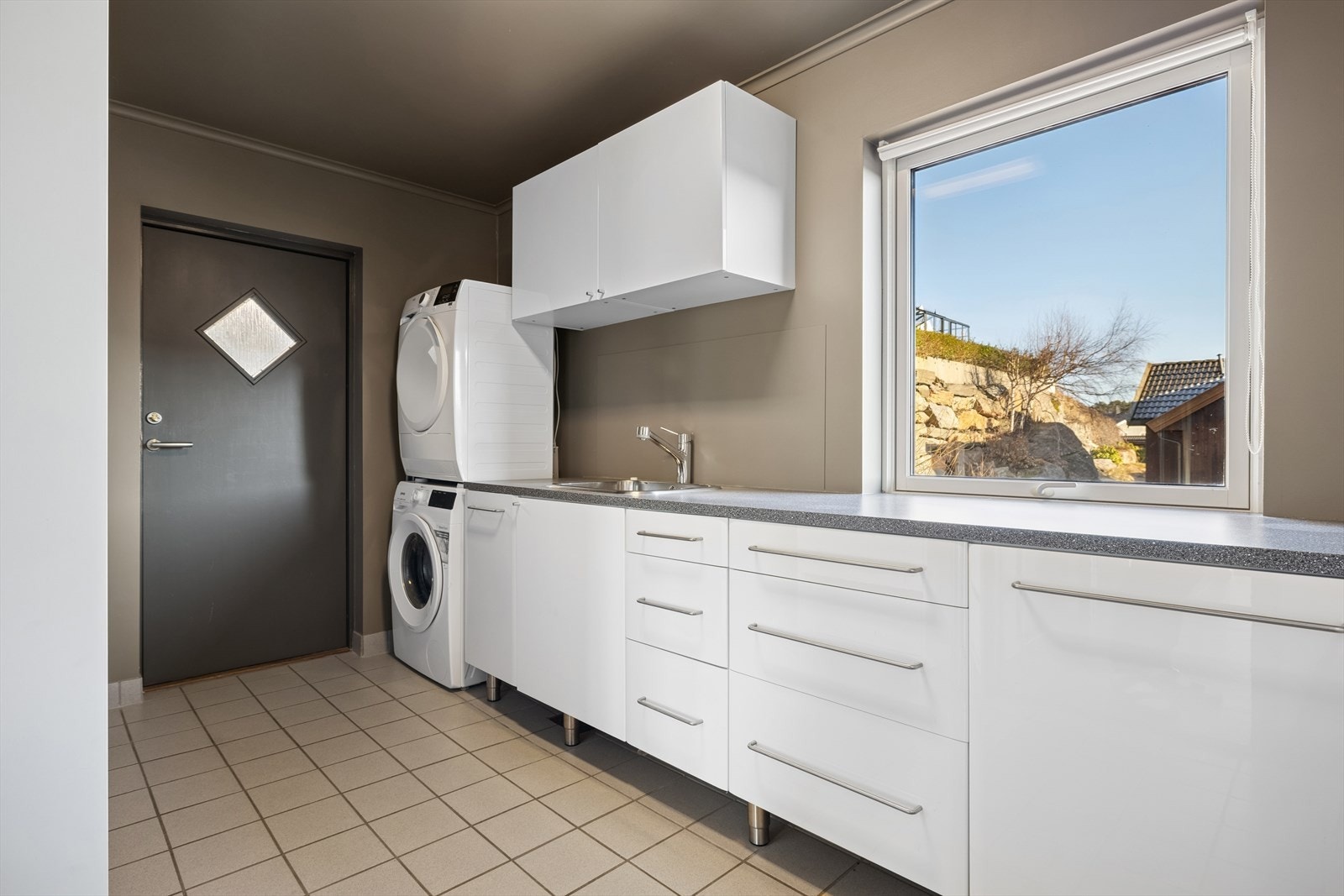 Romslig og praktisk vaskerom med god benkeplass og oppbevaringsmuligheter. Her er direkte utgang til platting med tørkemuligheter. Galleribilde