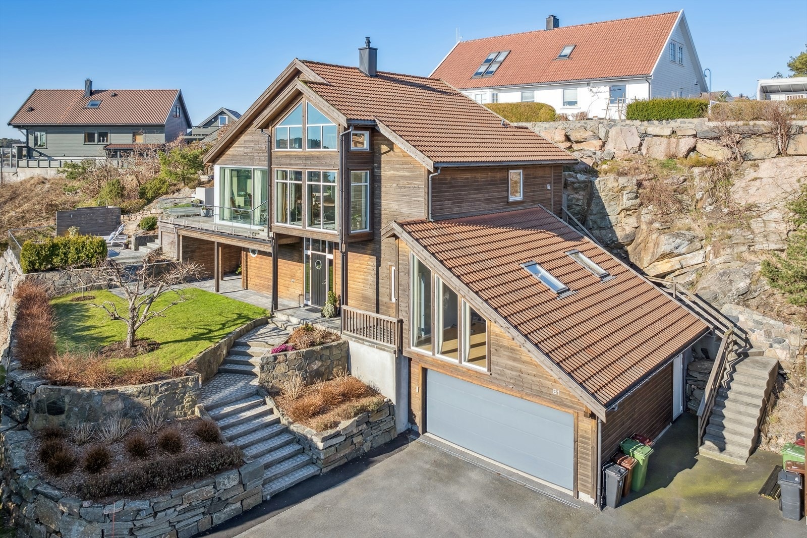 Asfaltert oppkjørsel med plass for parkering, dobbelgarasje med el-billader og bod i bakkant Galleribilde