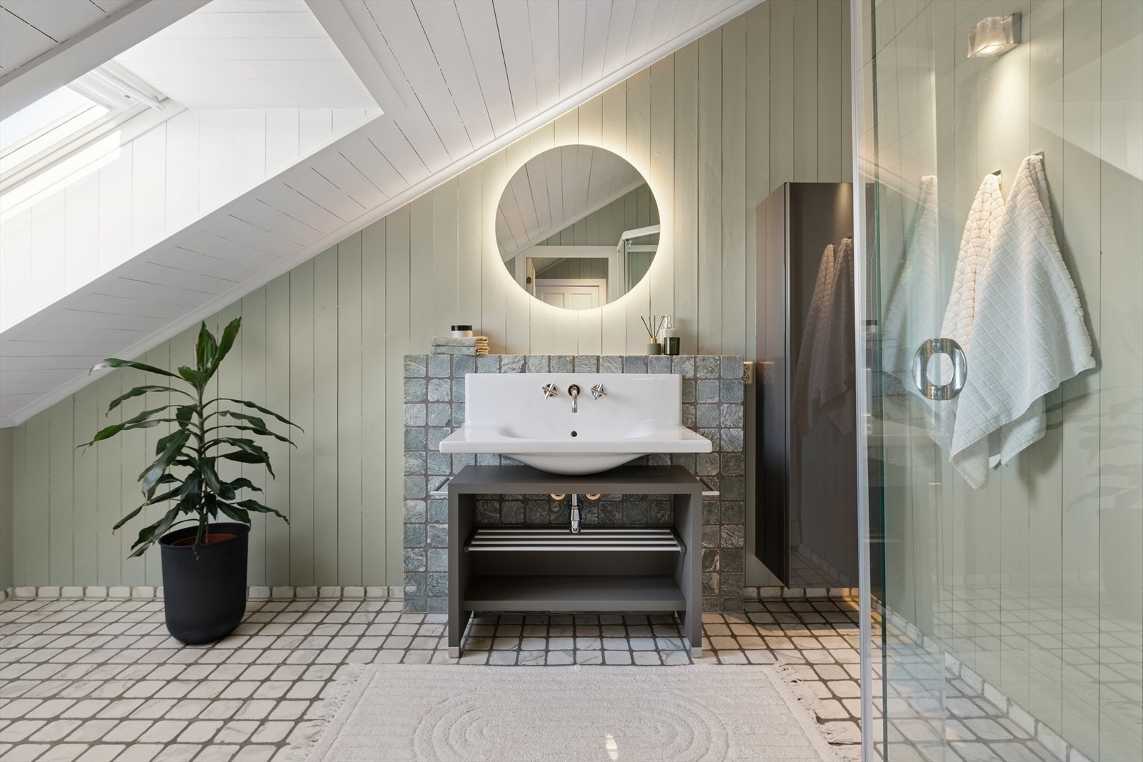 Delikat bad i loftsetasjen. Rommet er utstyrt med veggmontert toalett, dusjkabinett, servant, innredning og speil. Galleribilde