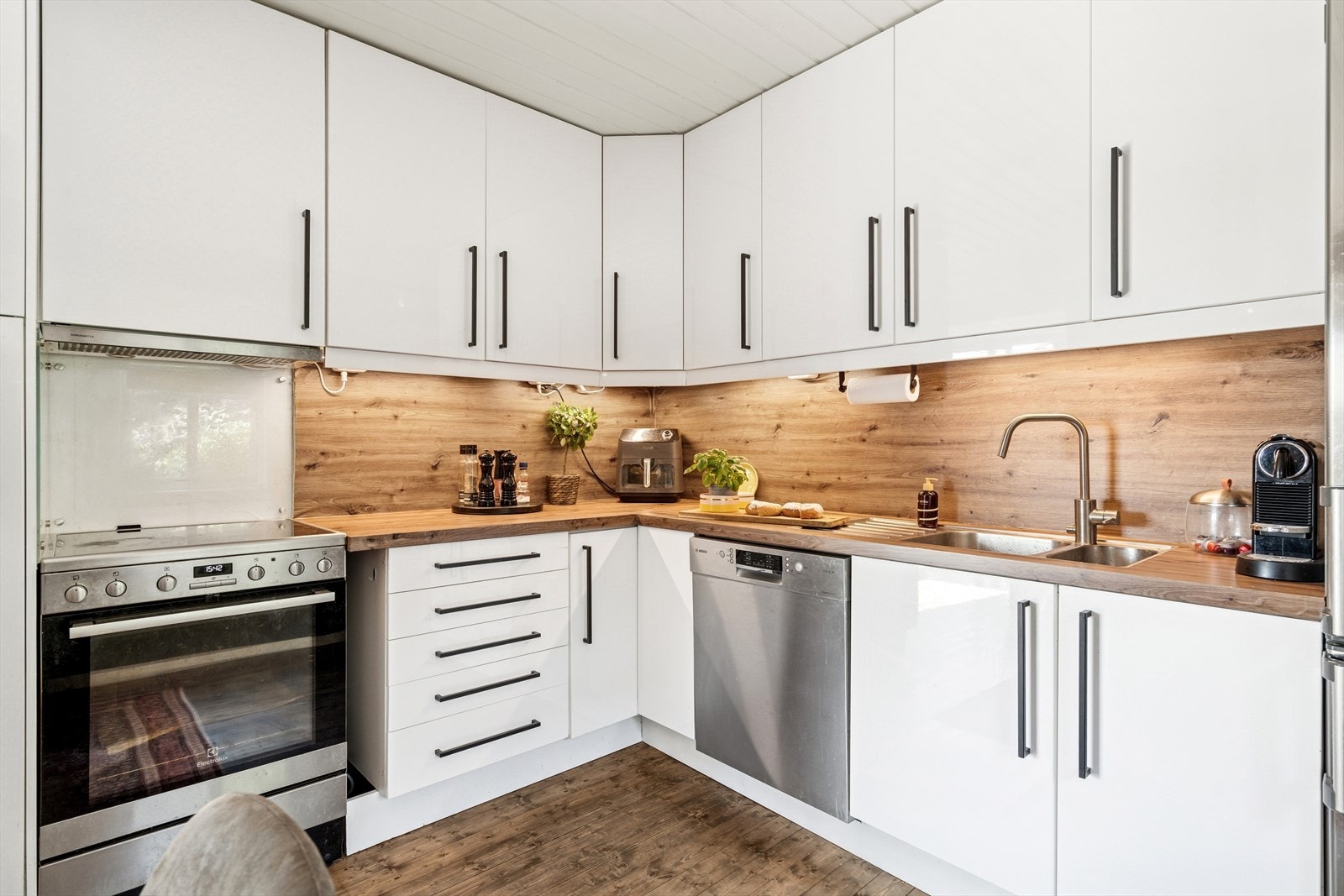 Det er en benkeplate og glassplate over benken. Kjøkkenet er utstyrt med frittstående komfyr, oppvaskmaskin og kjøleskap. Galleribilde