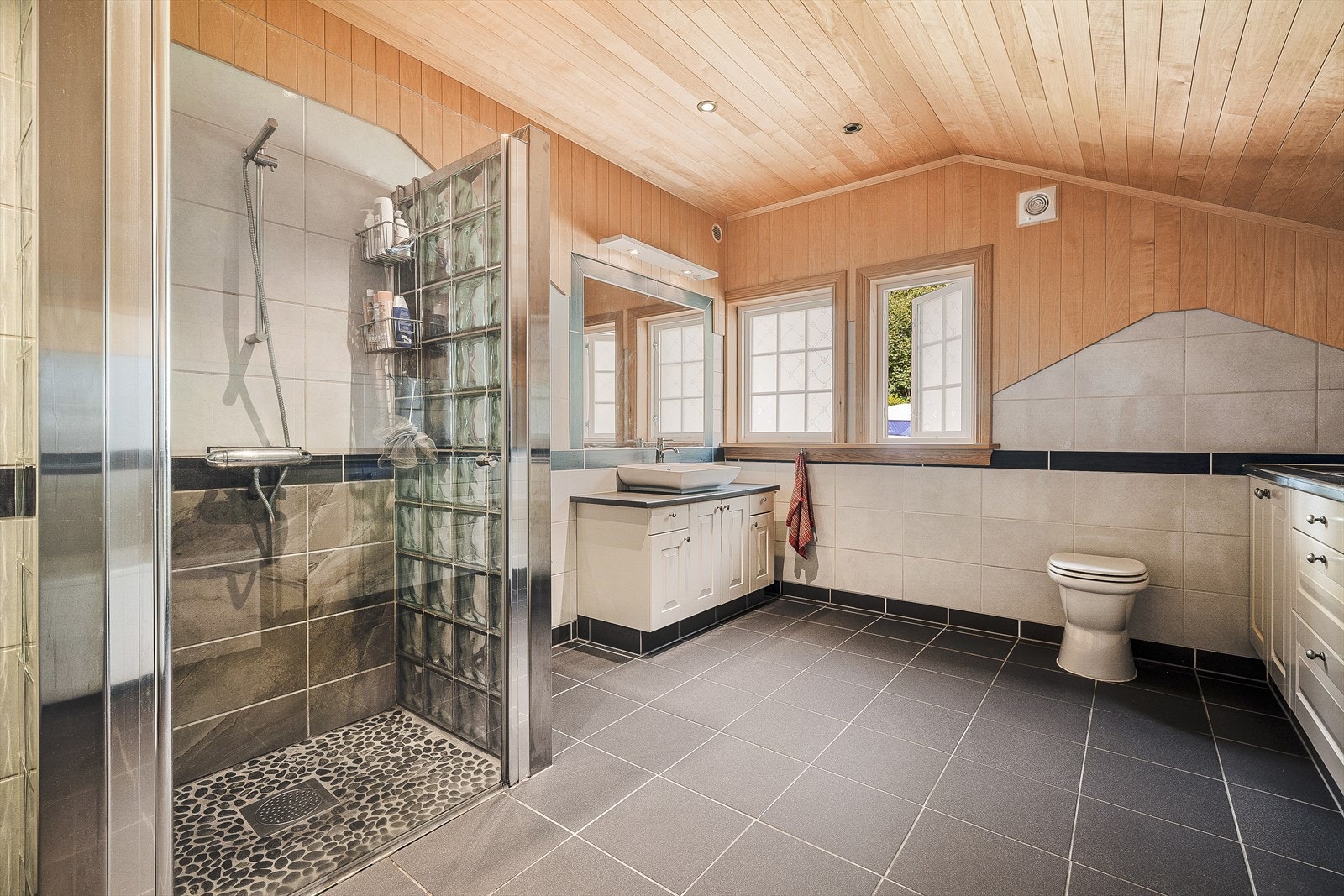 Baderommet i 2. etg. Her har man varme i gulvet, dusjhjørne med rullesteinsunderlag og rikelig med skap og skuffeseksjoner. Her et det godt med oppbevaringsplass! I tillegg har man badekar, som er helt perfekt etter en lang dag i skog og mark. Galleribilde