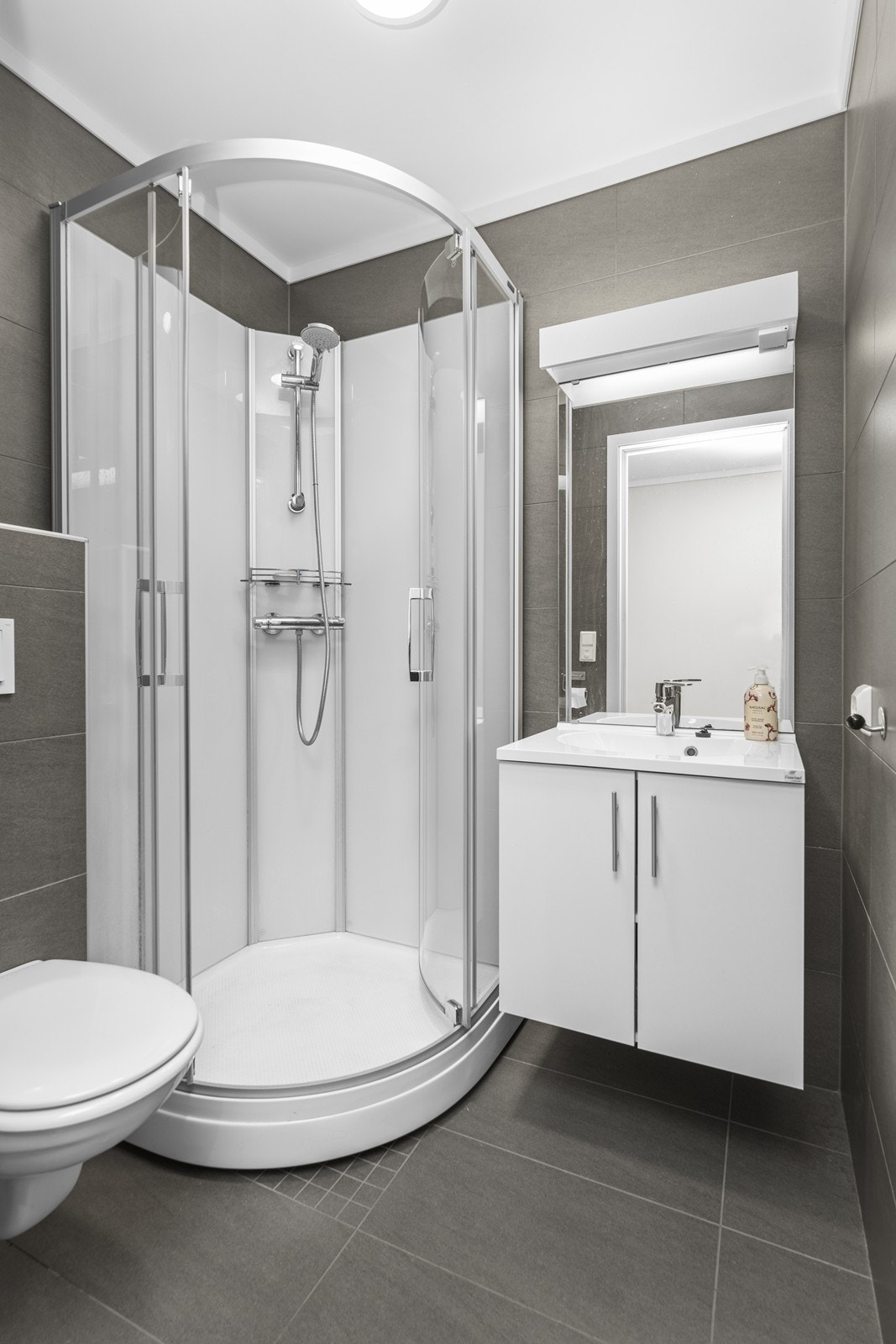 Badet i 1. etg (2 av 2) - praktisk innredet med dusjkabinett og vegghengt toalett Galleribilde