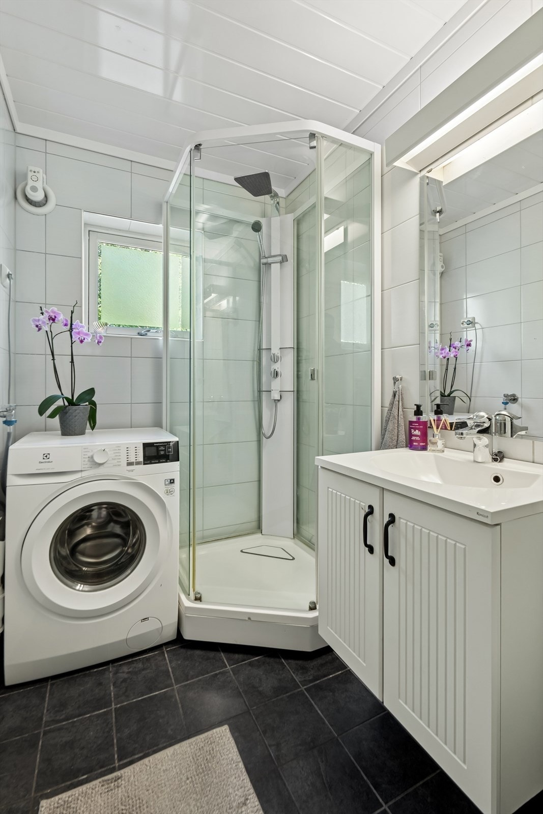 Badet er flislagt og har innredning med vask, dusjkabinett, toalett og opplegg for vaskemaskin. Galleribilde