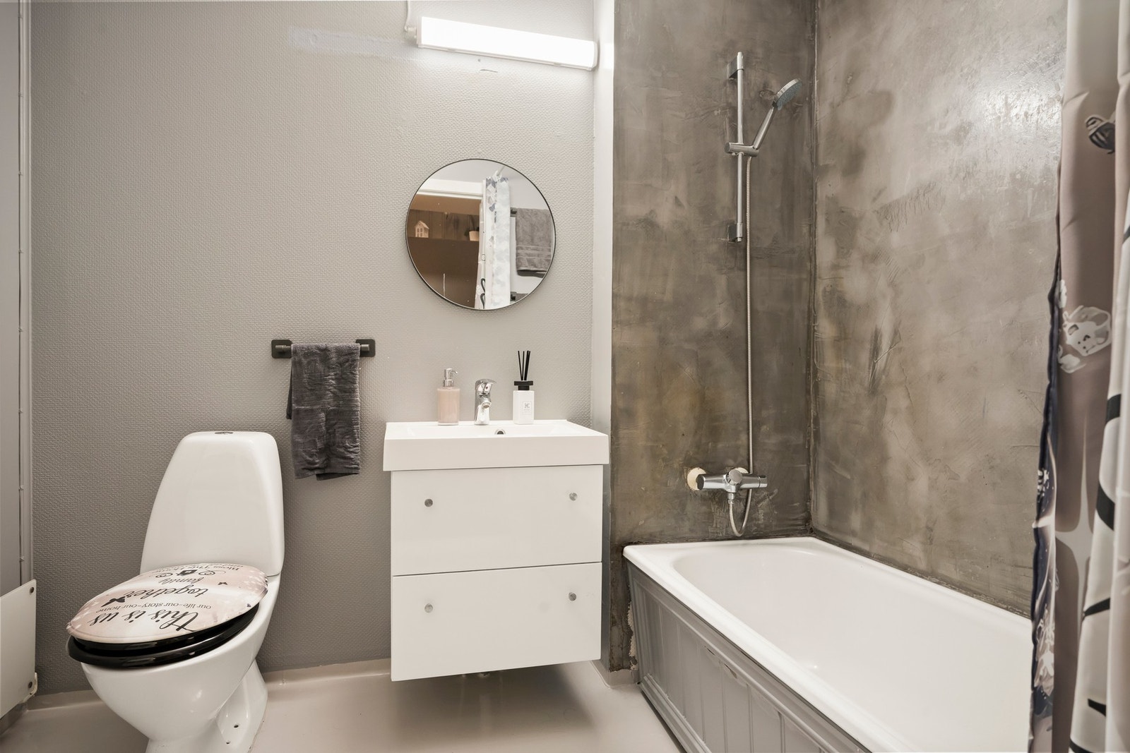 Badet er utstyrt med badekar, servantseksjon med skuffer og heldekkende komposittvask, speil med lys, høyskap og gulvmontert wc. Galleribilde