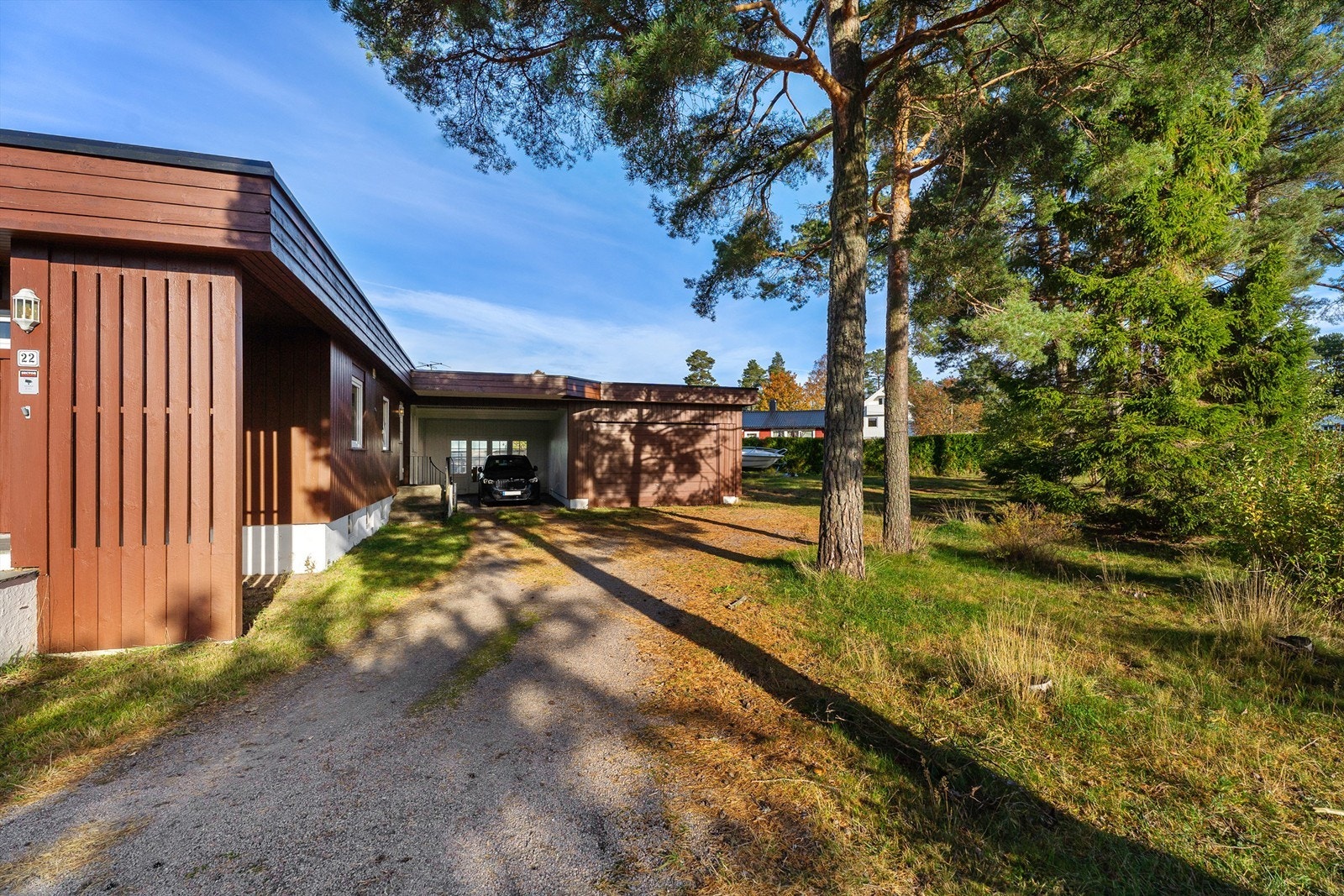 Innkjøring med carport og garasje i underetasjen samt frittstående garasje til høyre. Galleribilde