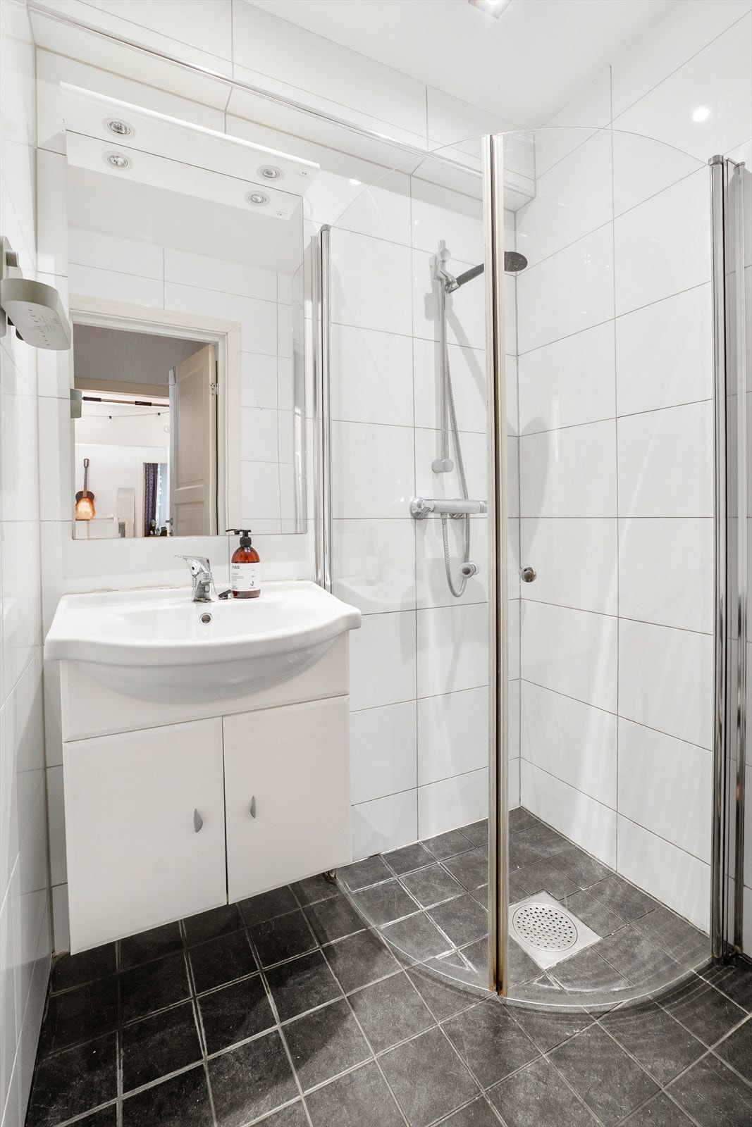 Over servanten er det montert et speil med overlys som bidrar til både romfølelse og funksjonalitet. Det er dusjhjørne med innfellbare glassdører og dusjarmatur med hånddusj. Galleribilde