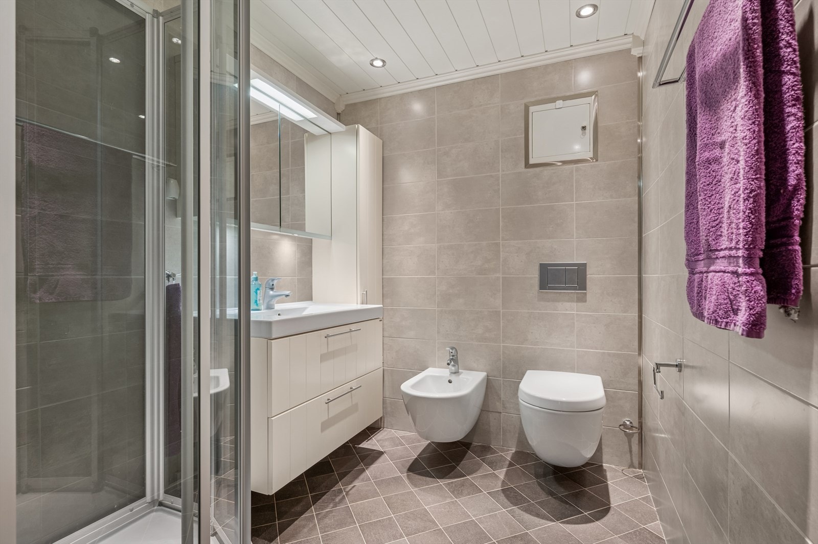 Bad, i underetasje, har fliser på vegger og himling har mdfpanelplank med downlights. Galleribilde