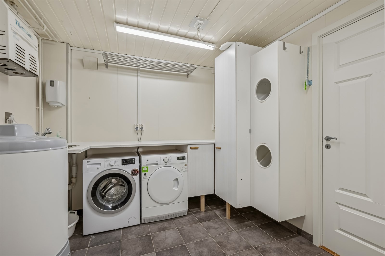 Enkel innredning med glatte overflater og laminat benkeplate med nedfelt utslagskum. Opplegg for vaskemaskin og plass for tørketrommel. Naturlig ventilering / ventil i yttervegg. Galleribilde