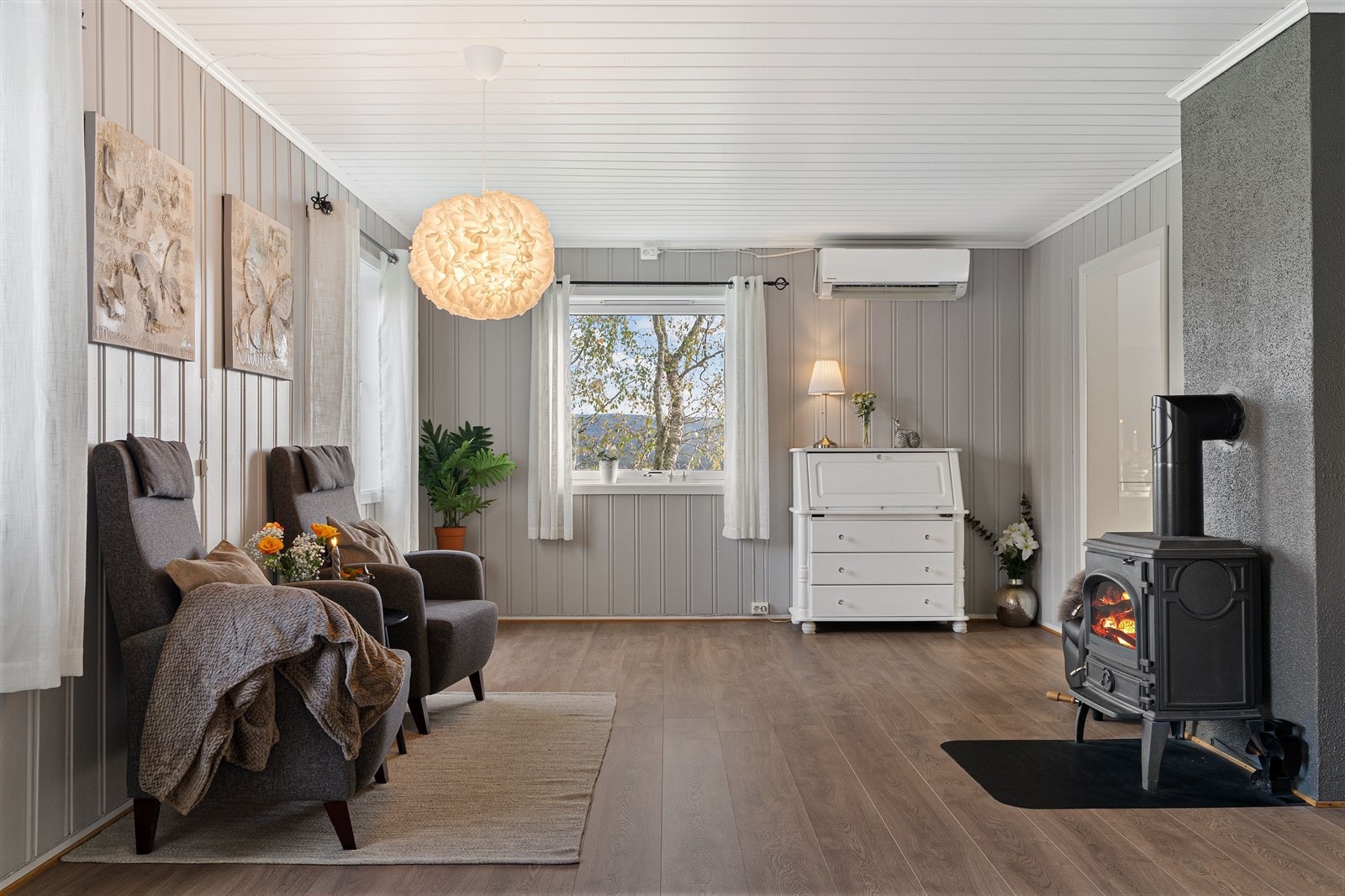 Den minste stuen har en lun atmosfære med både eldre peisovn og en varmepumpe fra 2015. Galleribilde
