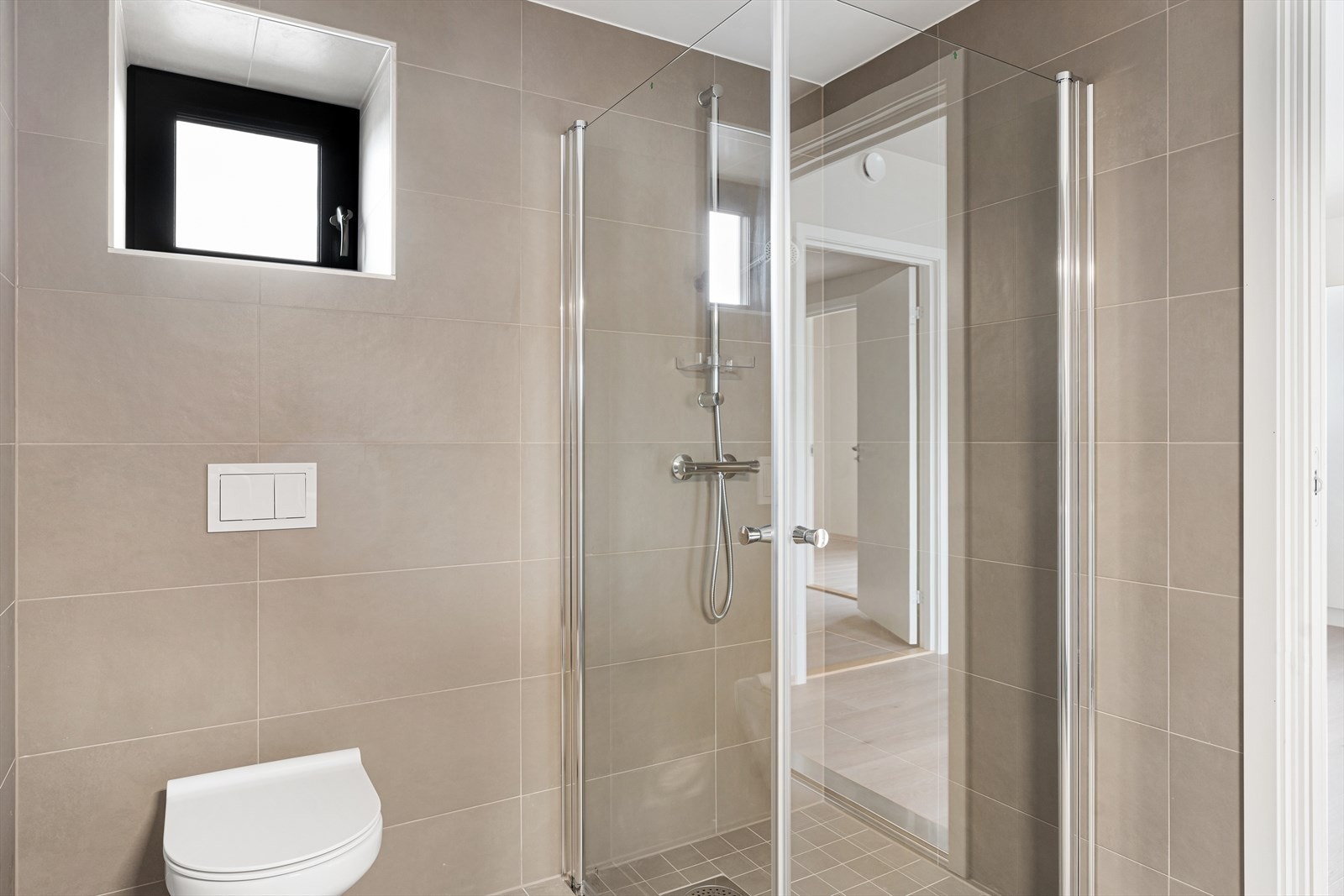 Badet har dusjhjørne, vegghengt toalett og innredning med servant Galleribilde