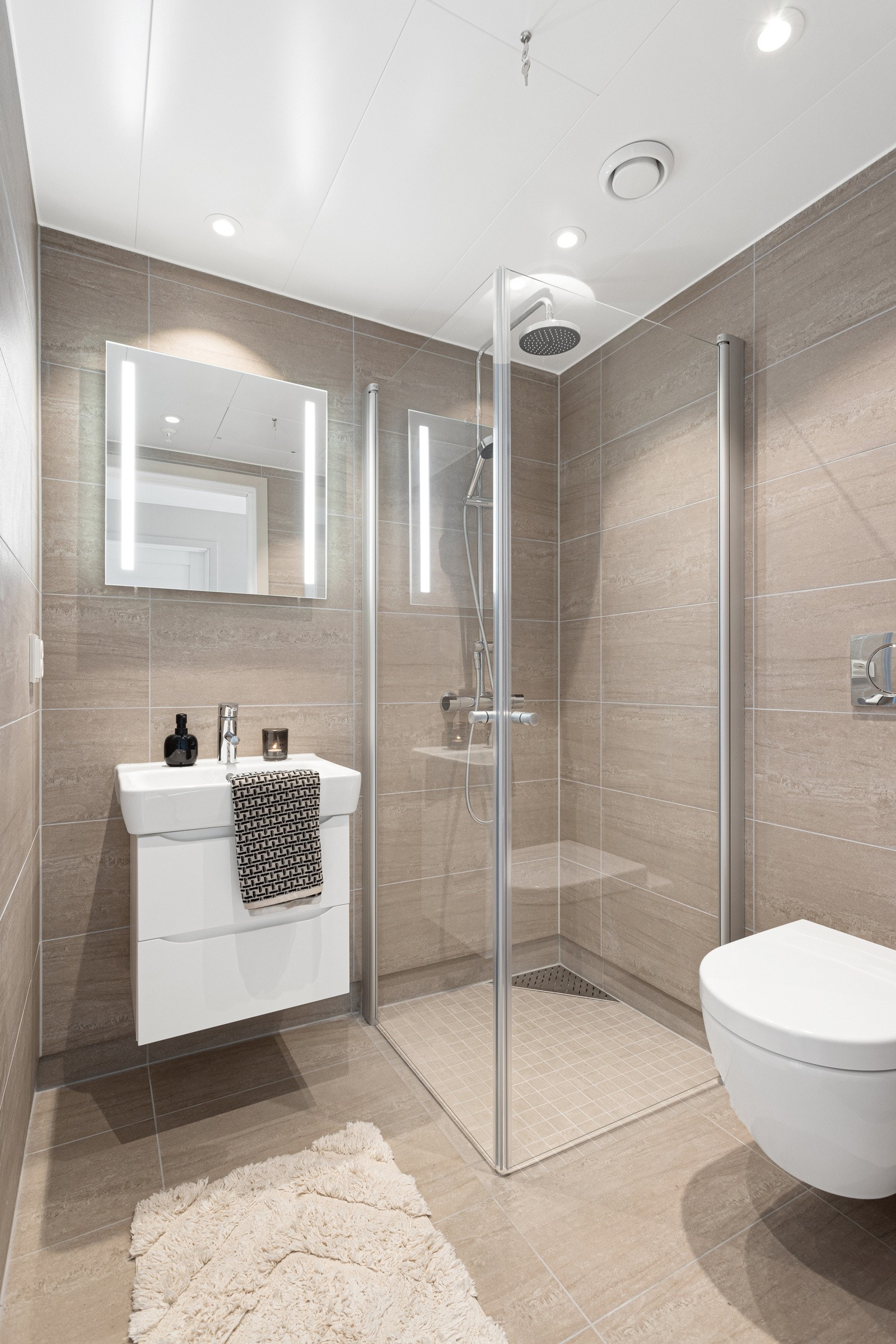 Gjestebadet innenholder dusjhjørne med glassvegger, servantskap og vegghengt toalett. Galleribilde