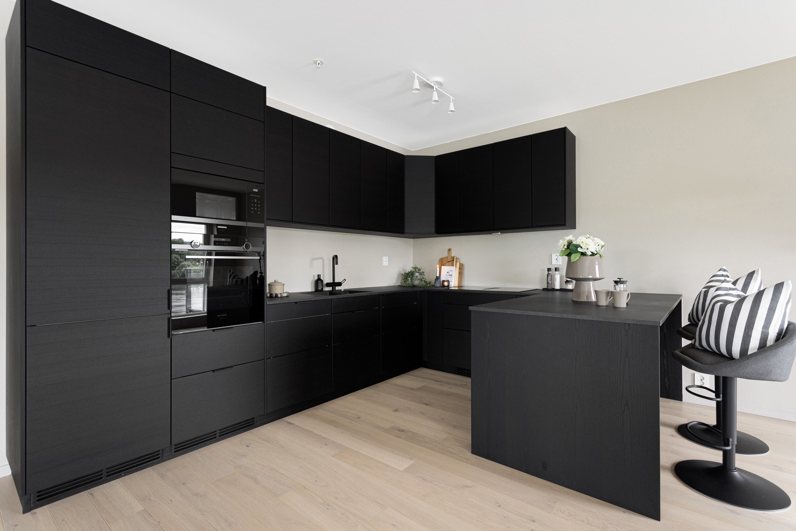 Flott kjøkkeninndedning med sorte fronter som har godt med skapplasss i form av benkeskap og overskaper. Galleribilde