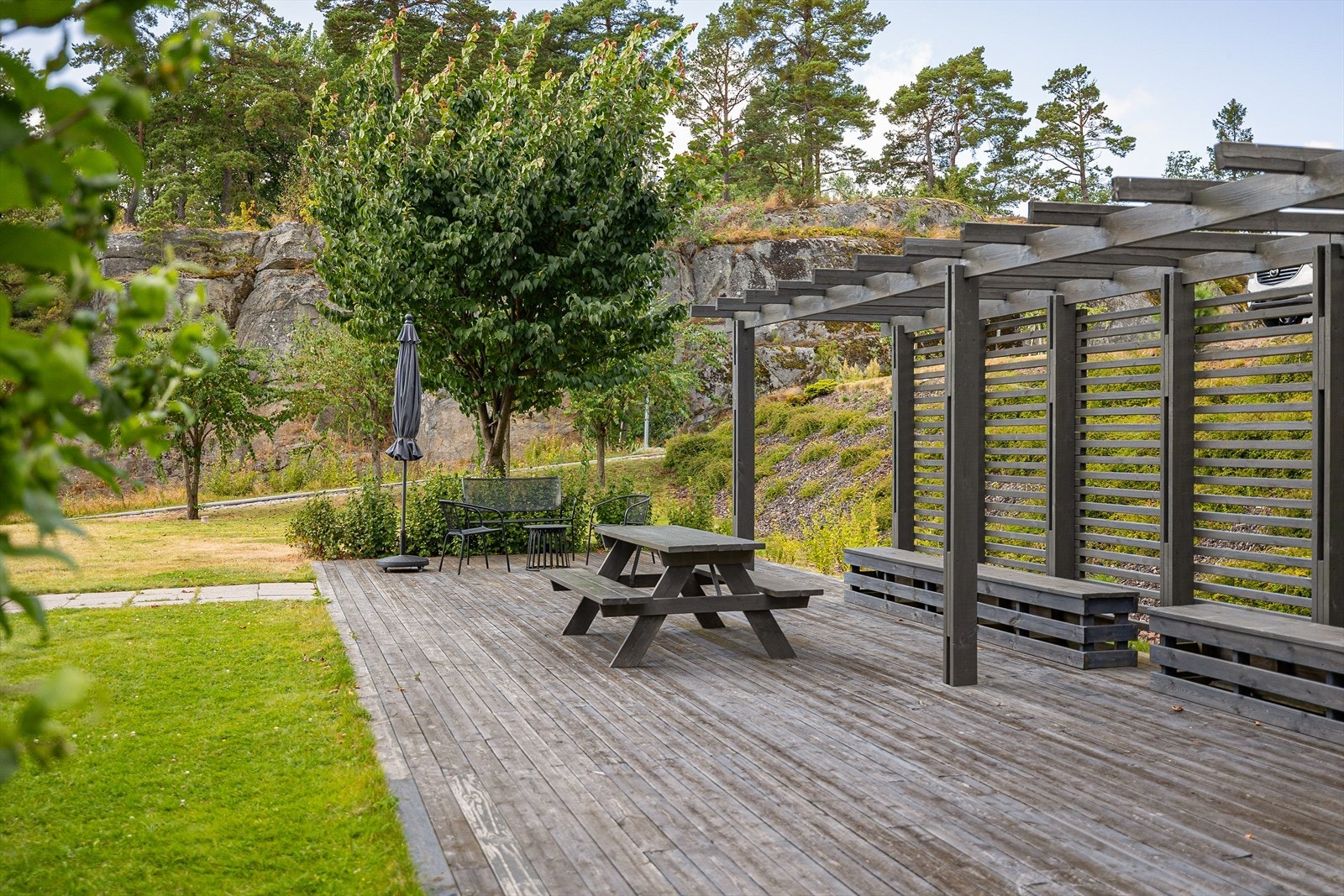 På nordsiden av bygget finner du et flott fellesareal, nøye utformet for trivsel og samvær. Her er det anlagt en koselig platting med benker og bord - et perfekt sted for en kopp kaffe i morgensola eller hyggelige samtaler med naboene på ettermiddagen. Galleribilde
