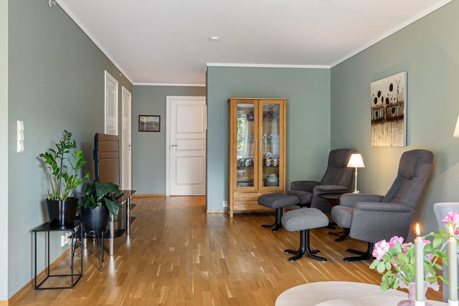 Gulvet er kledd i en vakker trestavs eikeparkett som gir rommet et elegant og tidløst preg. Den varme trestrukturen tilfører naturlig lys og en behagelig følelse. Veggene er malt i en myk, pen grønnfarge som skaper en beroligende og innbydende atmosfære. Galleribilde