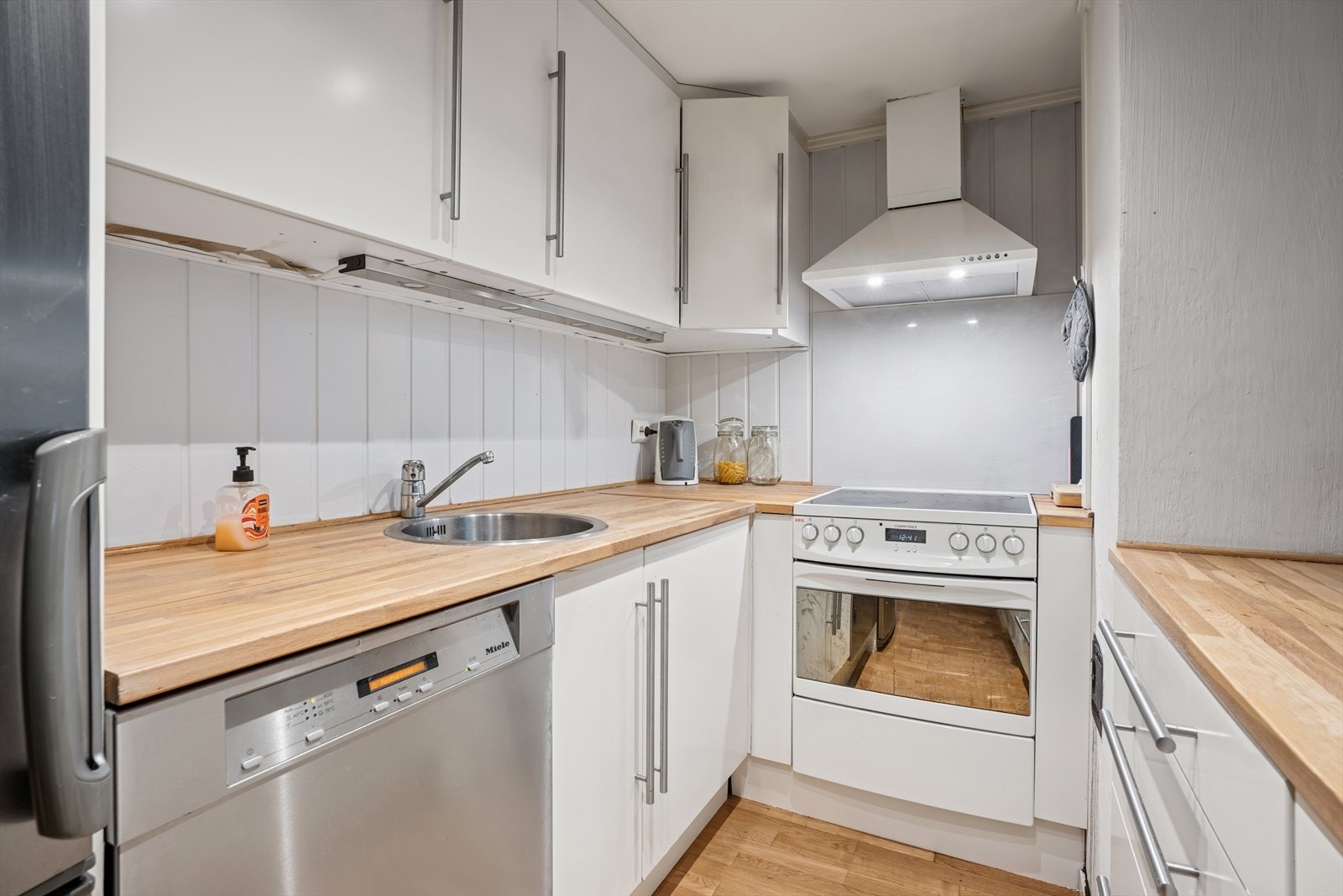 Kjøkkenet i leiligheten har hvite, glatte fronter og heltre benkeplate i hvit utførelse med nedfelt kjøkkenkum. Galleribilde