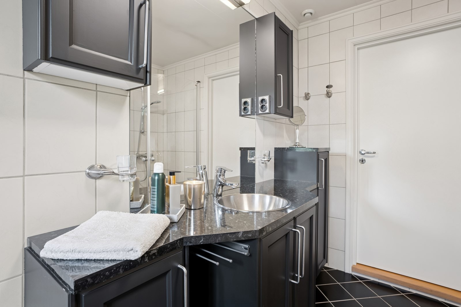 Baderomsinnredningen har sorte, profilerte fronter, mørk benkeplate med nedfelt vask. Galleribilde