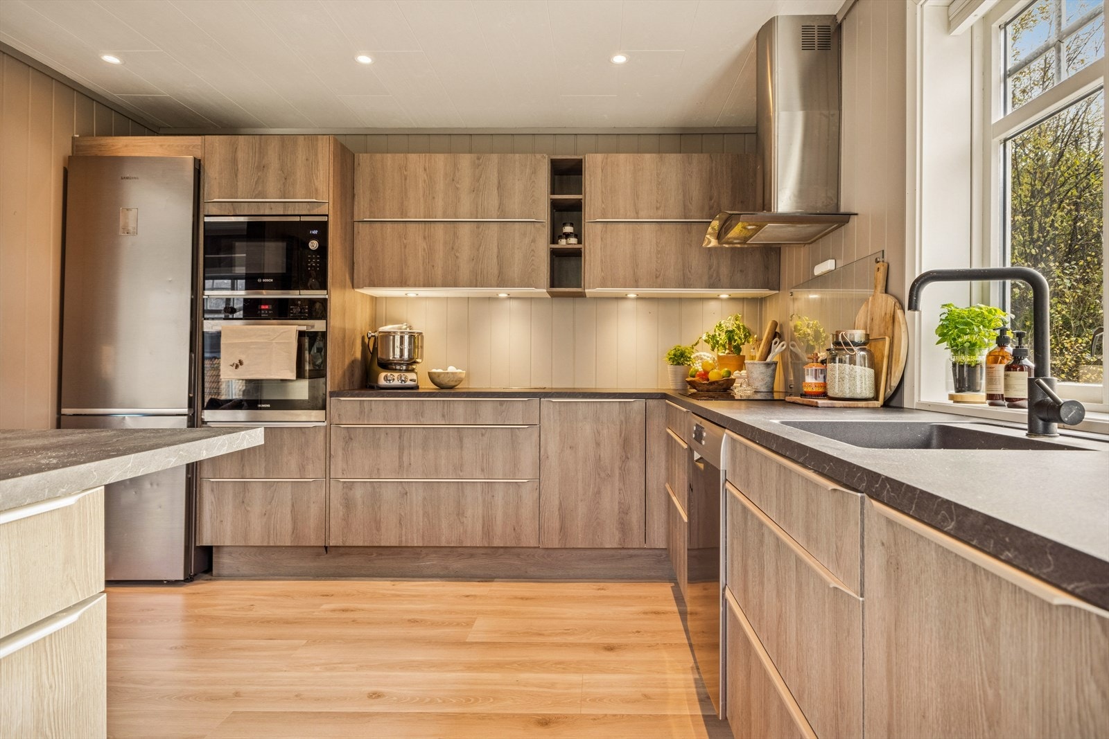 Innredningen består av lyse trefinérskap med rene linjer og minimalistiske håndtak, noe som gir et elegant og stilrent preg Galleribilde