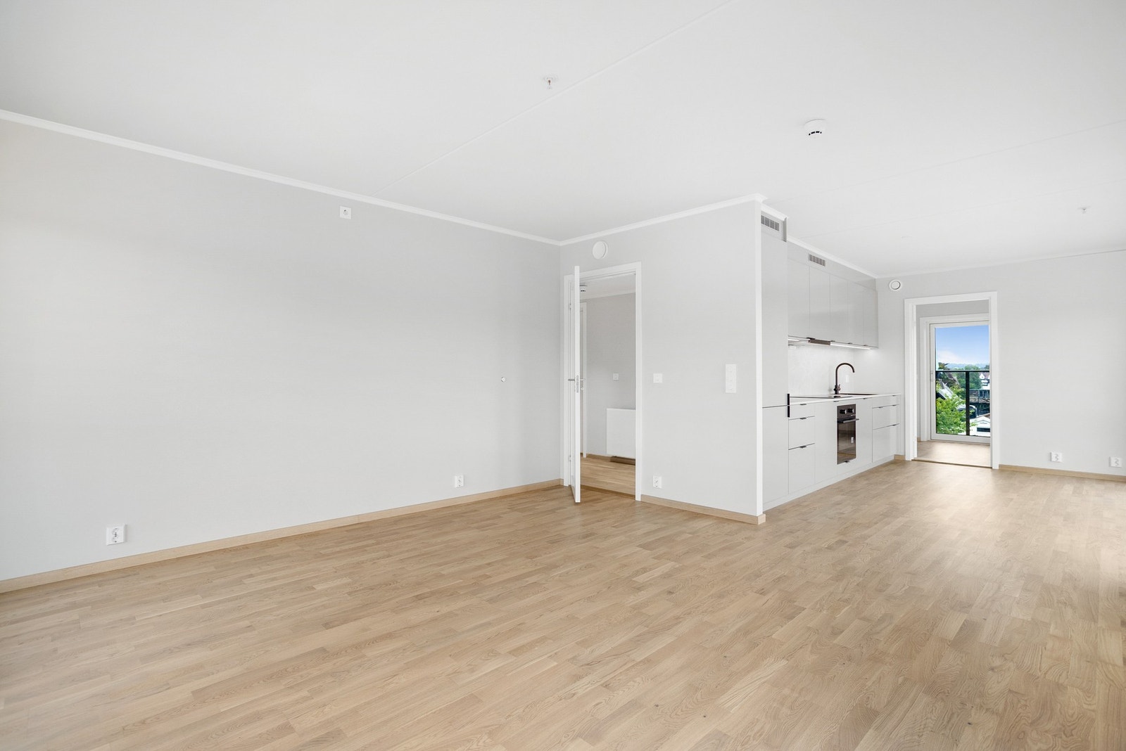 Romslig stue i sammenheng med kjøkken, med god plass til spise- og sittegruppe Galleribilde