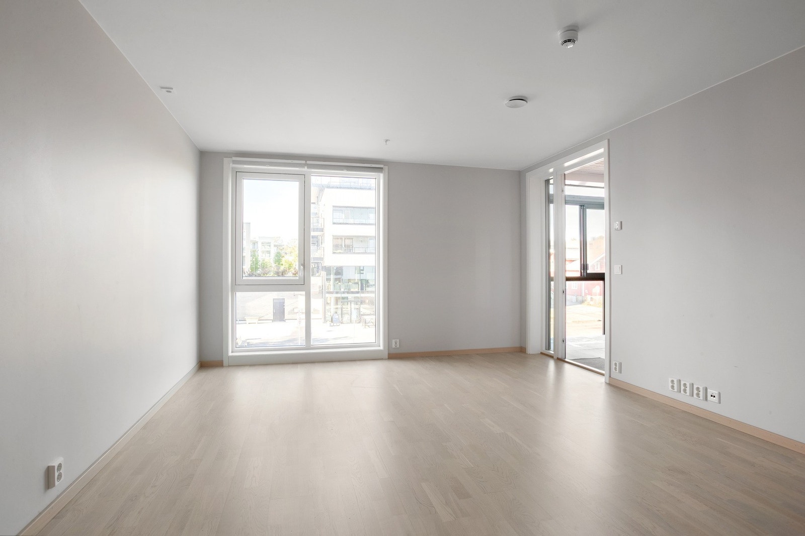 Lys stue med parkett og store vindusflater som slipper inn godt med naturlig lys Galleribilde